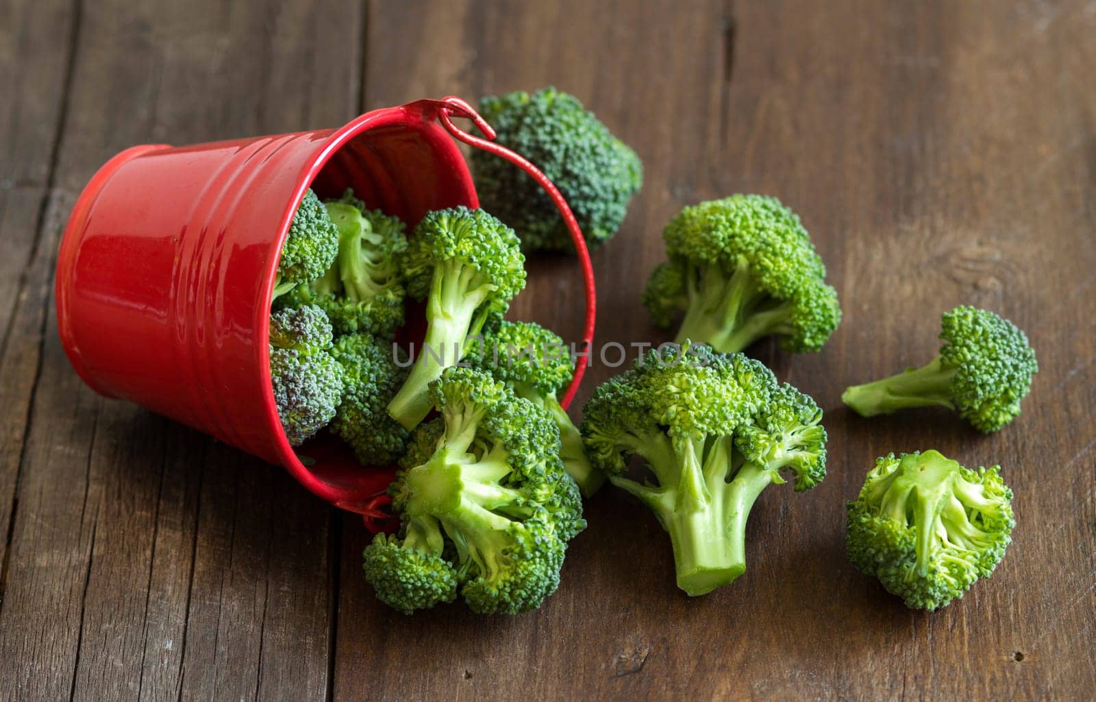 Green broccoli in red bucket on old wood