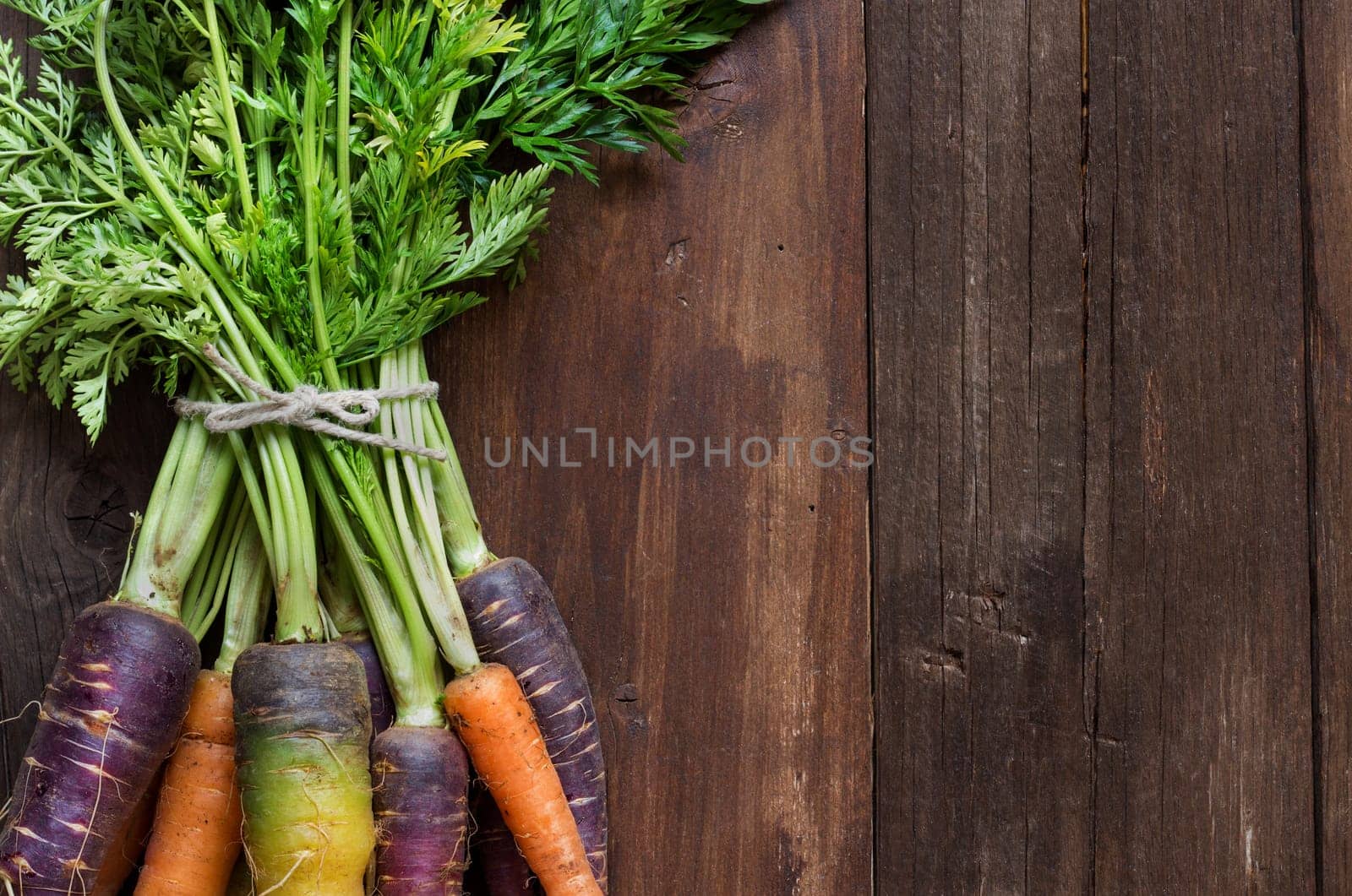 Fresh organic rainbow carrots with leaves on a wooden table