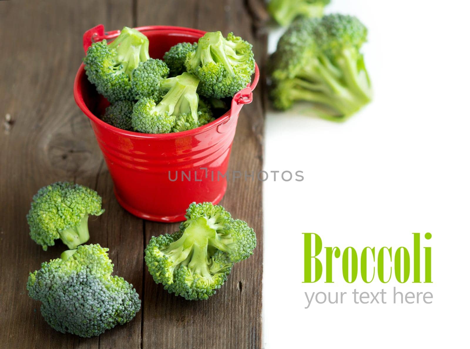 Green broccoli in red bucket on old wood