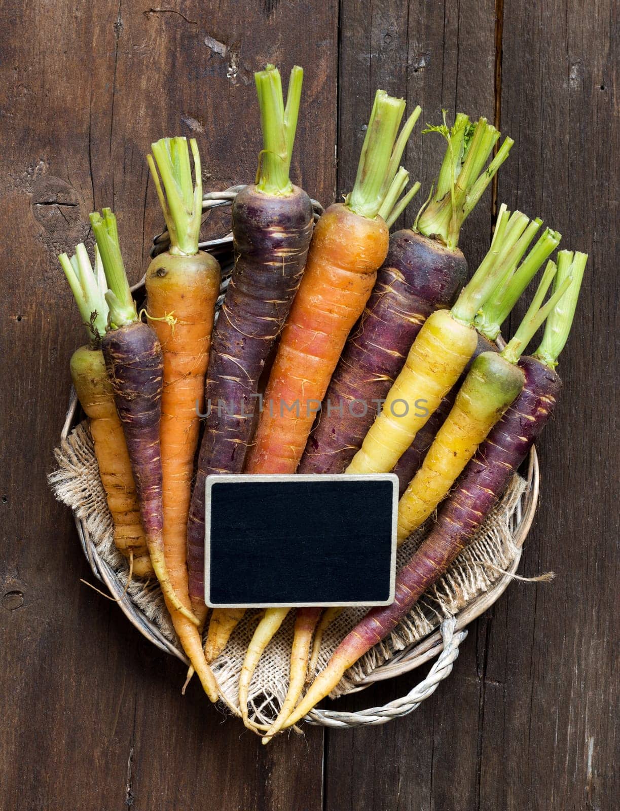 Fresh organic rainbow carrots and a small chalkboard on wood