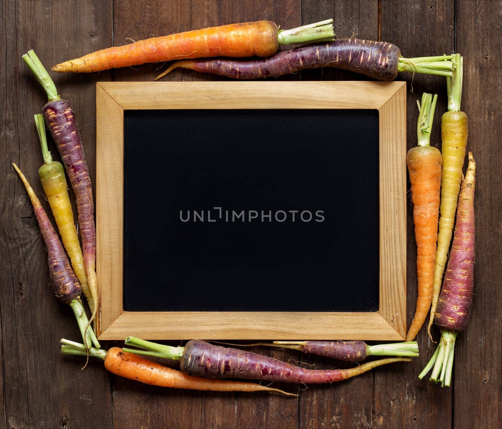 Fresh organic rainbow carrots and chalkboard on wood