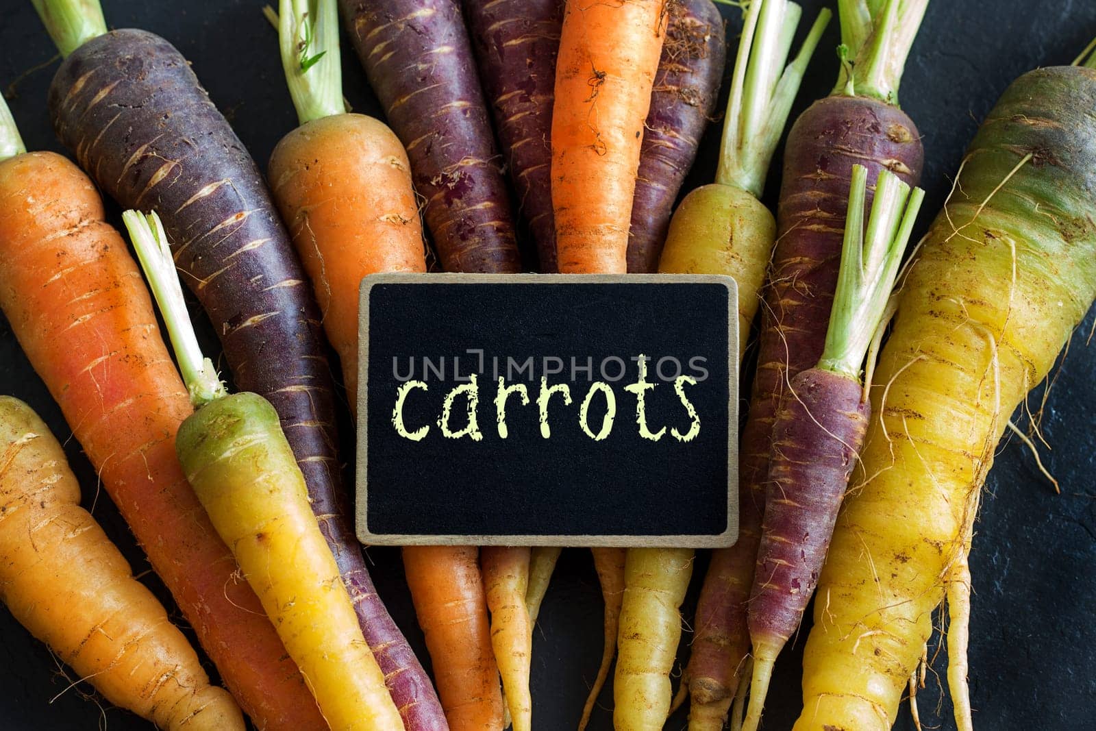 Fresh organic rainbow carrots and a small chalkboard on wood