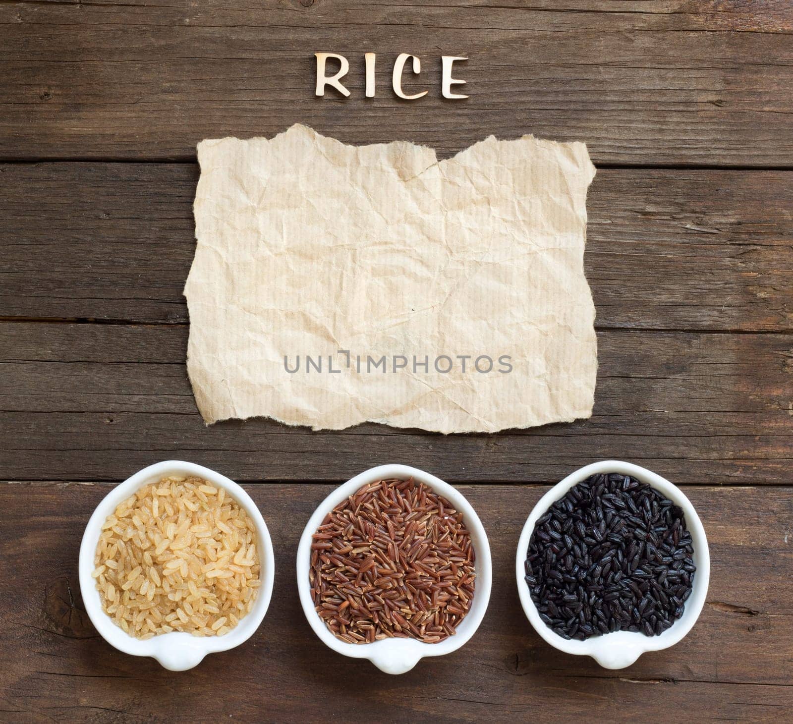 Variety of rice with craft paper and word Rice on wood