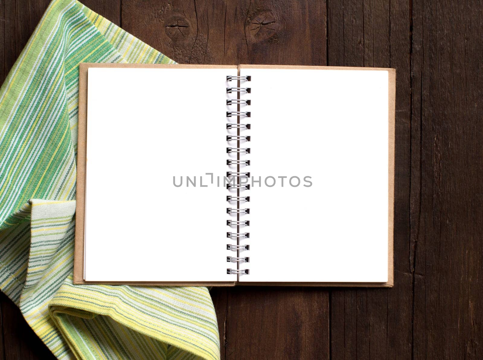 Notebook on a colorful napkin on wooden table