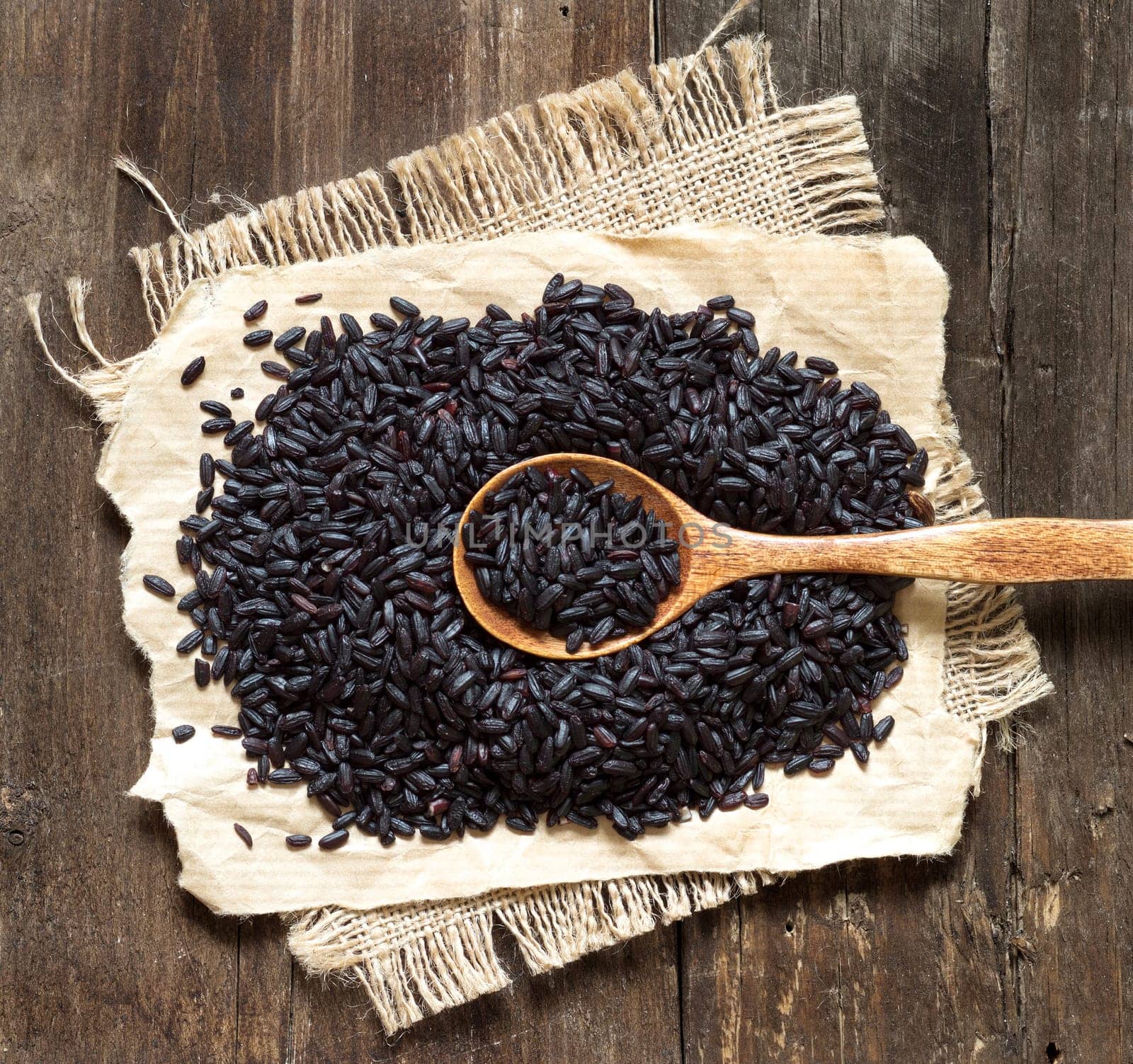 Black rice with a spoon on a wooden table