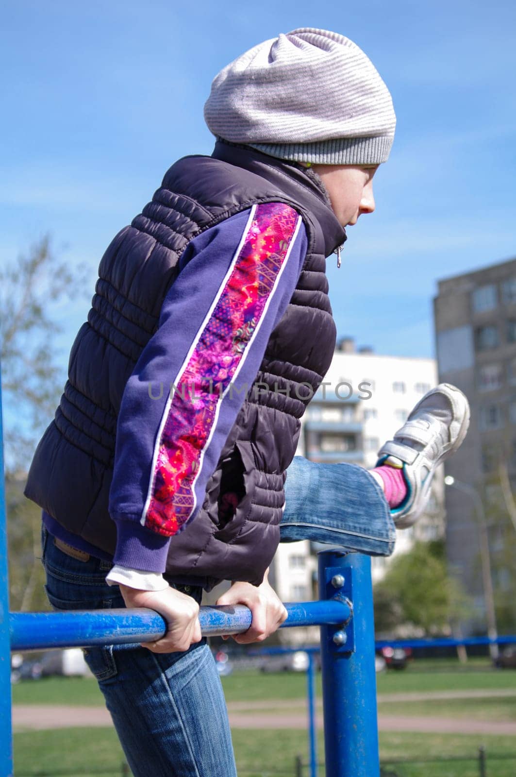 Young athletic girl hanging on horizontal bar