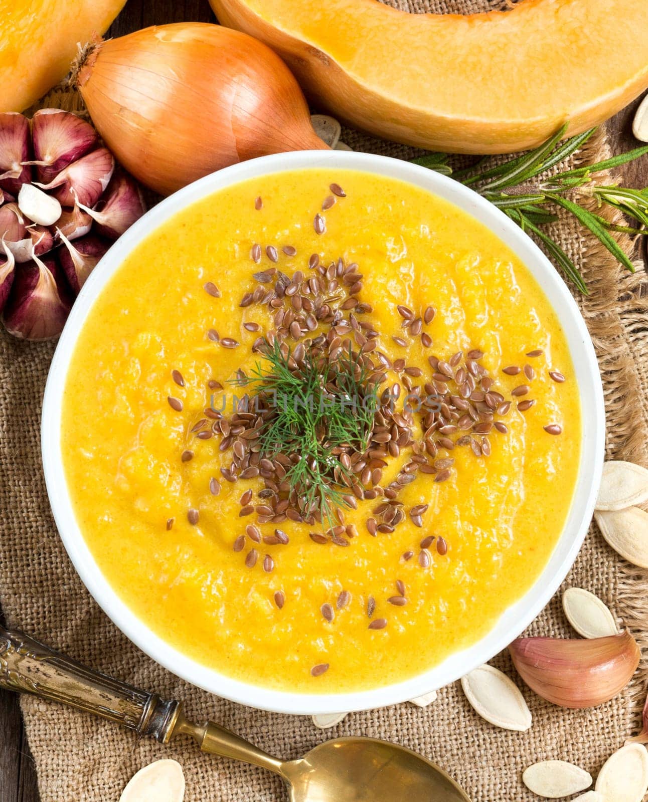 Fresh pumpkin soup with a spoon on a wooden table