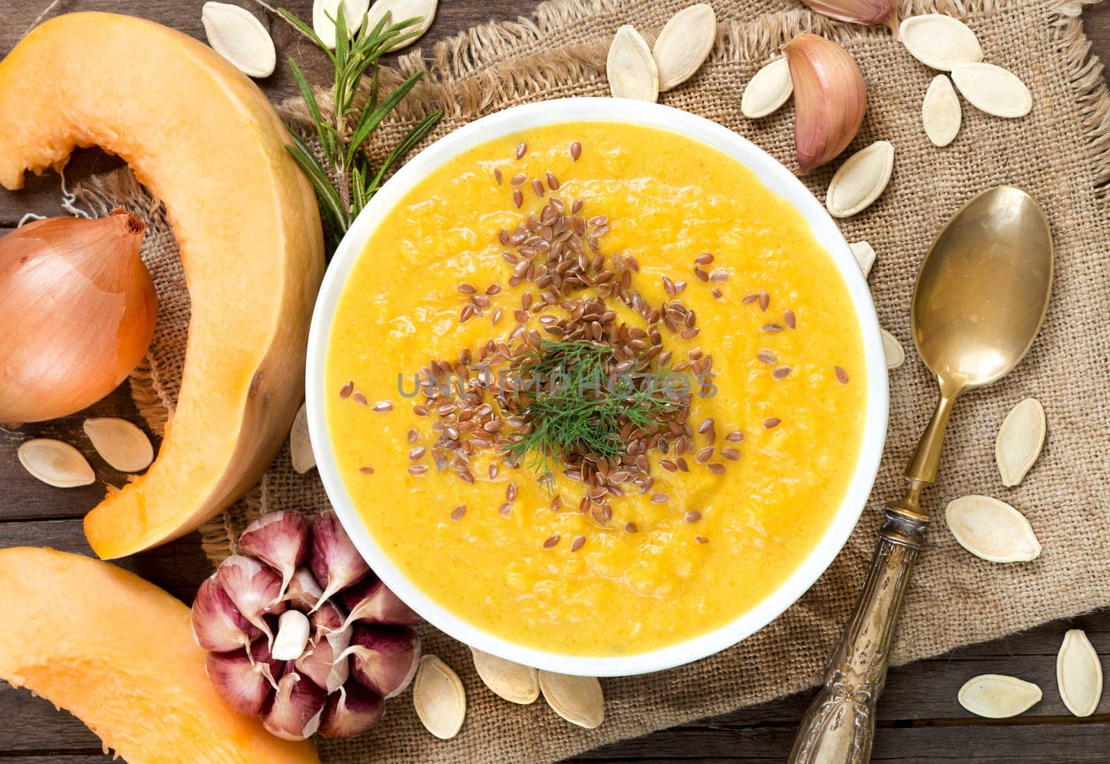 Fresh pumpkin soup with a spoon on a wooden table