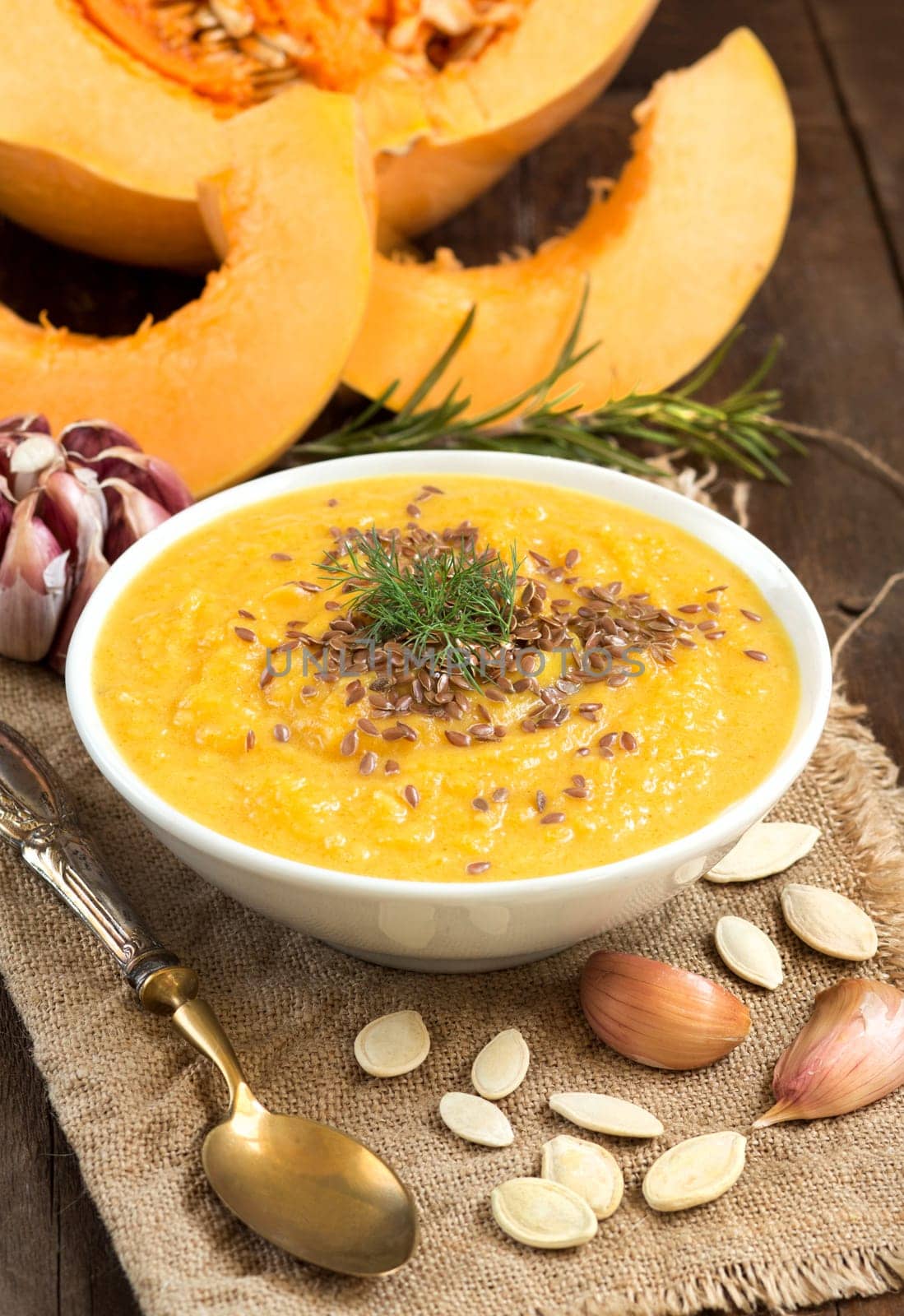 Fresh pumpkin soup with a spoon on a wooden table