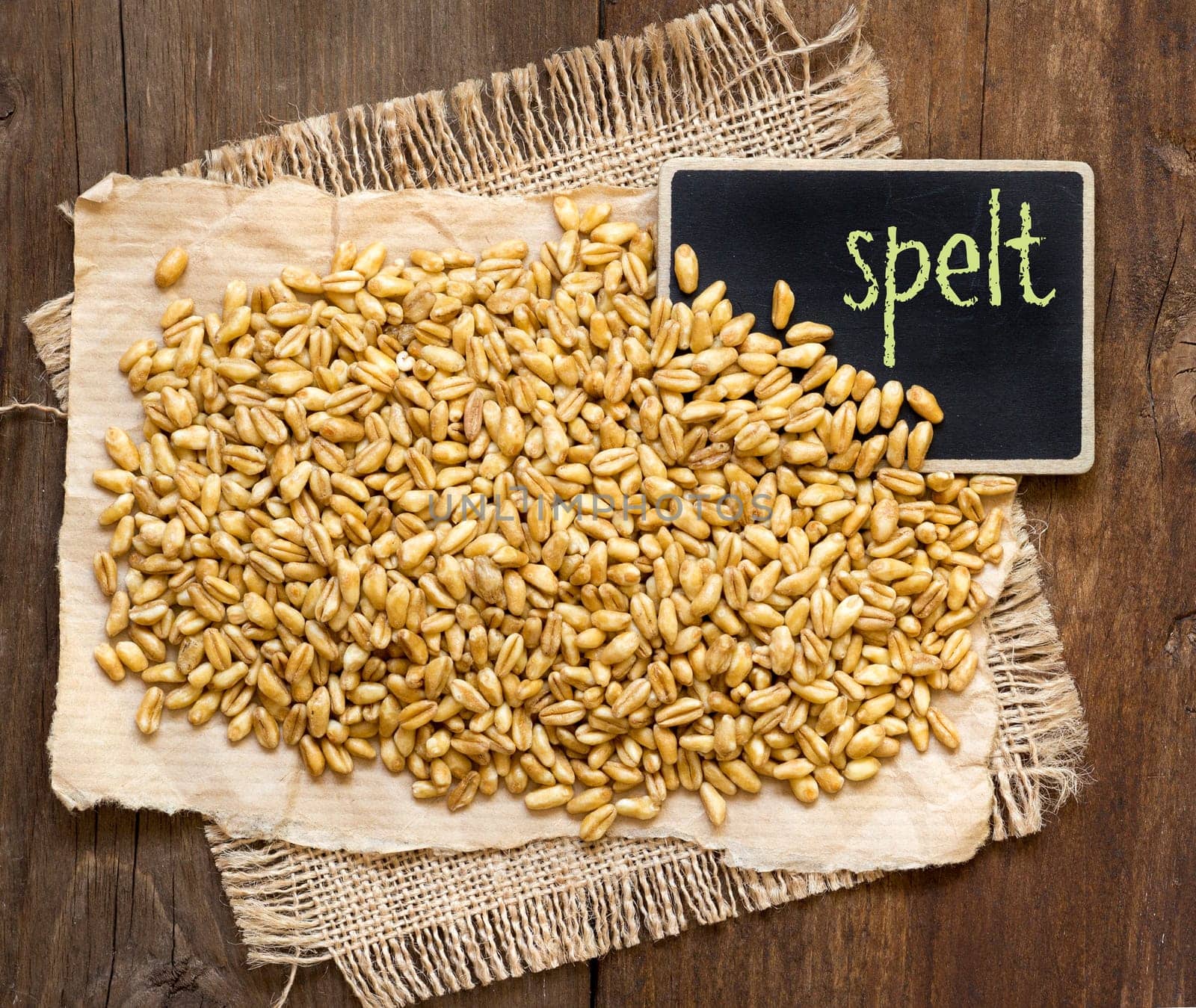 Raw organic spelt and small chalkboard on a wooden table