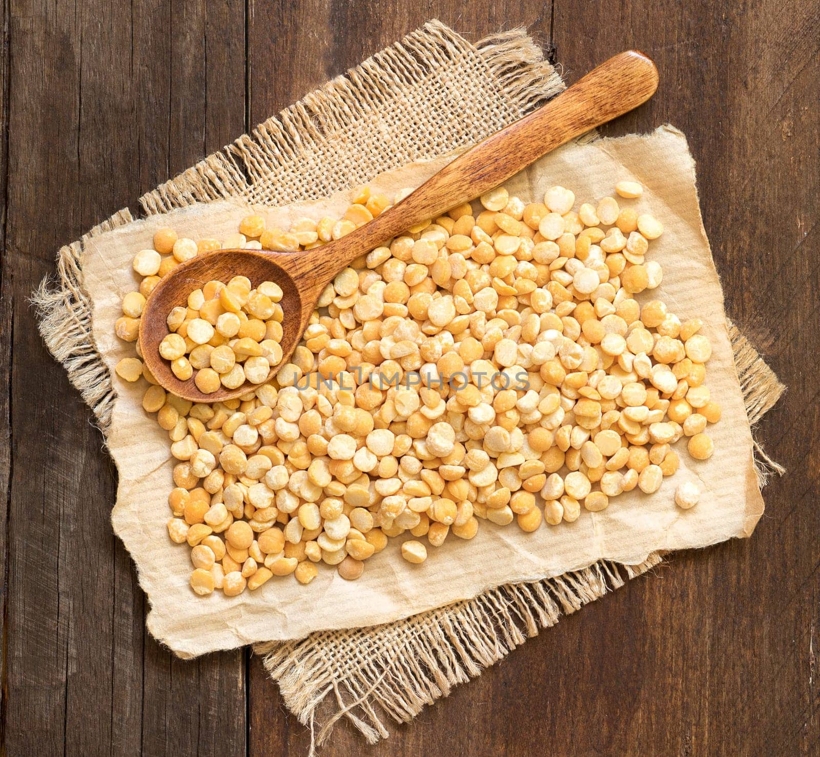Yellow peas with a spoon on a wooden table