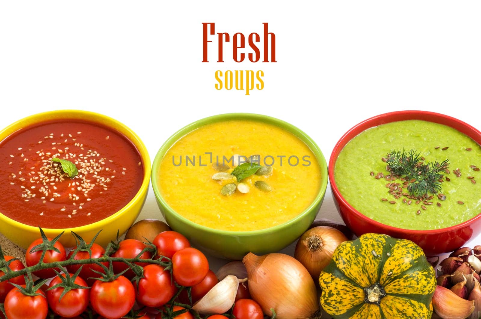 Three fresh soups in colorful bowls and vegetables