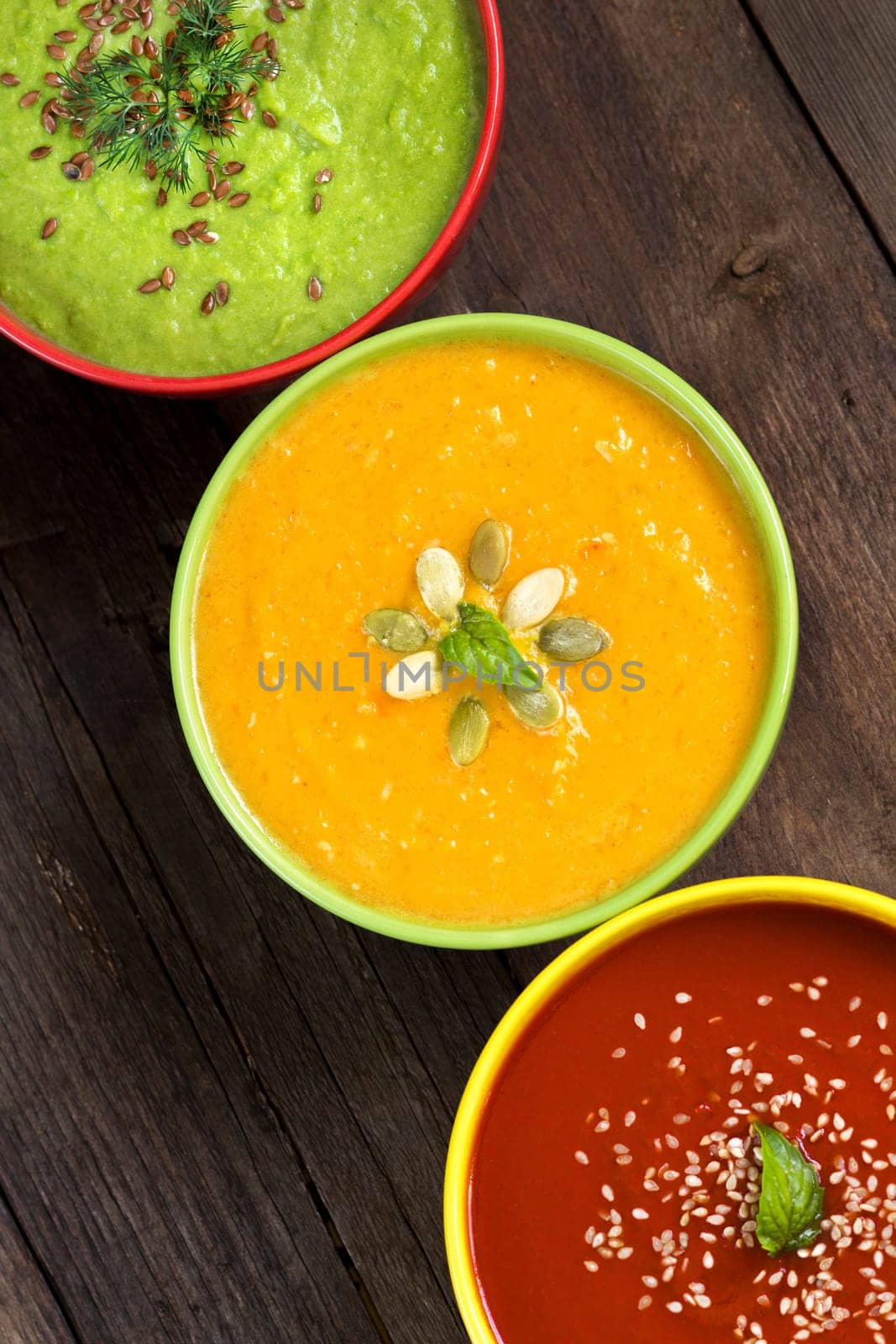 Tomatoe, pumpkin and green peas soups on a wooden table