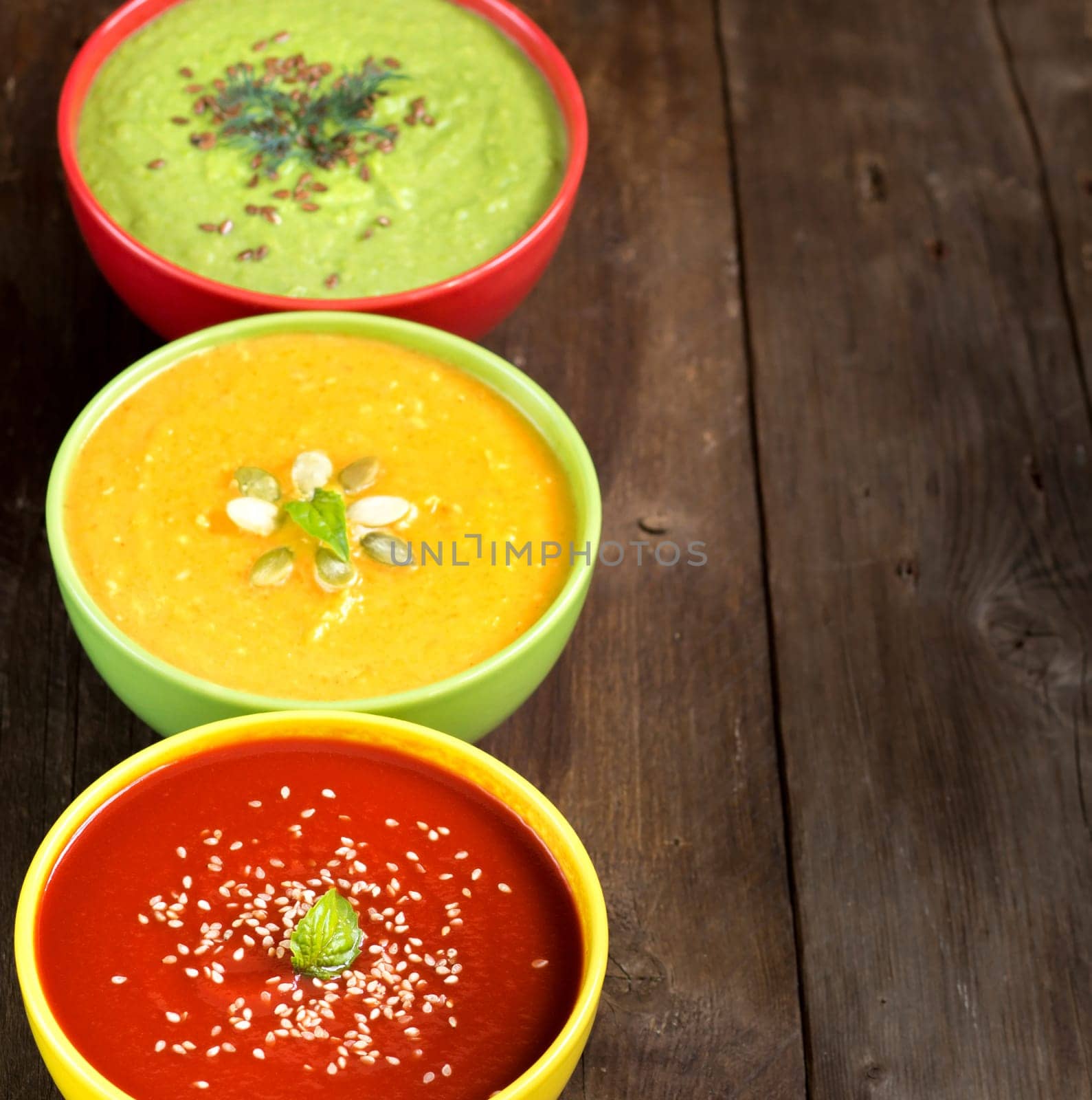 Tomatoe, pumpkin and green peas soups on a wooden table