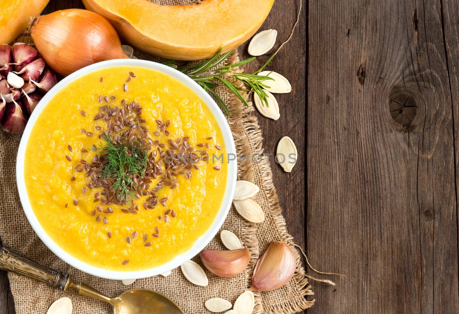 Fresh pumpkin soup with a spoon on a wooden table