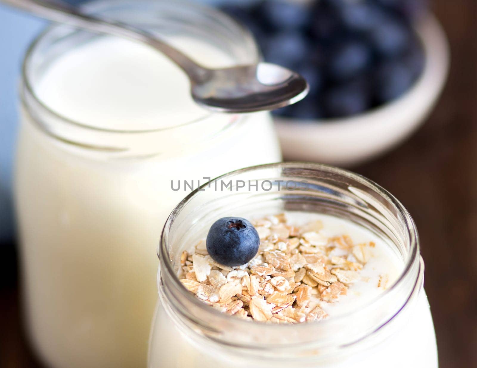 Jars of fresh natural yogurt with spoon and blueberries