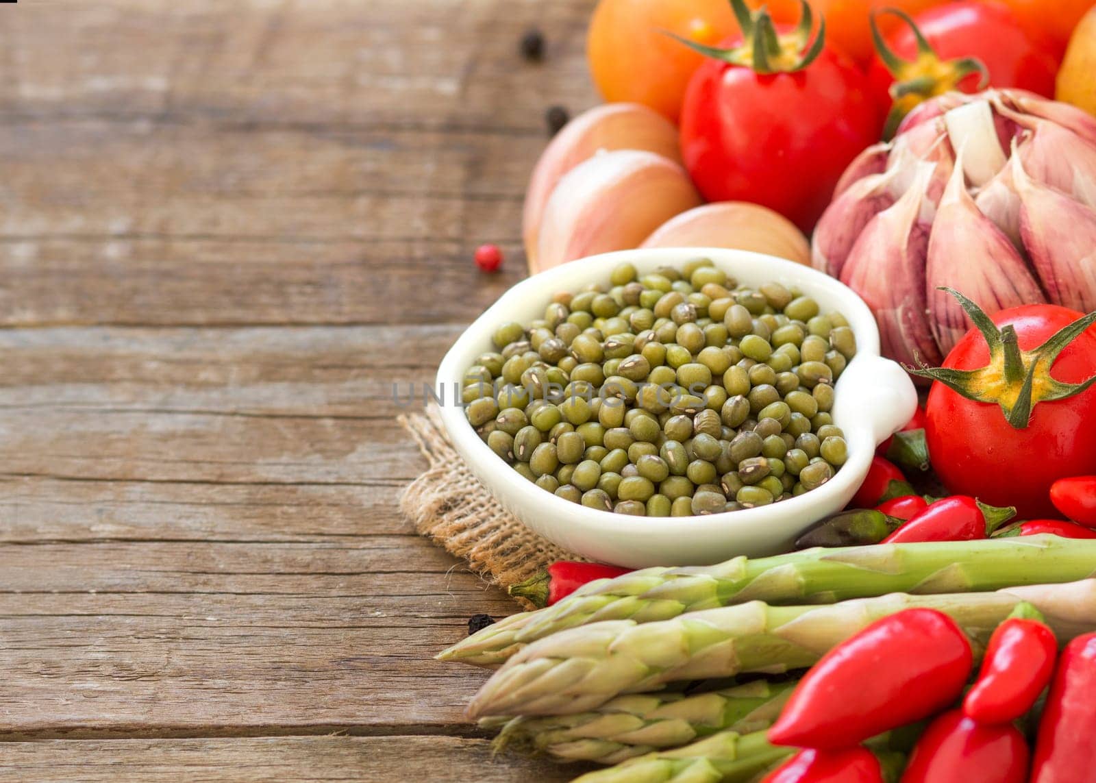 Mung beans in a bowl and vegetables on wooden table