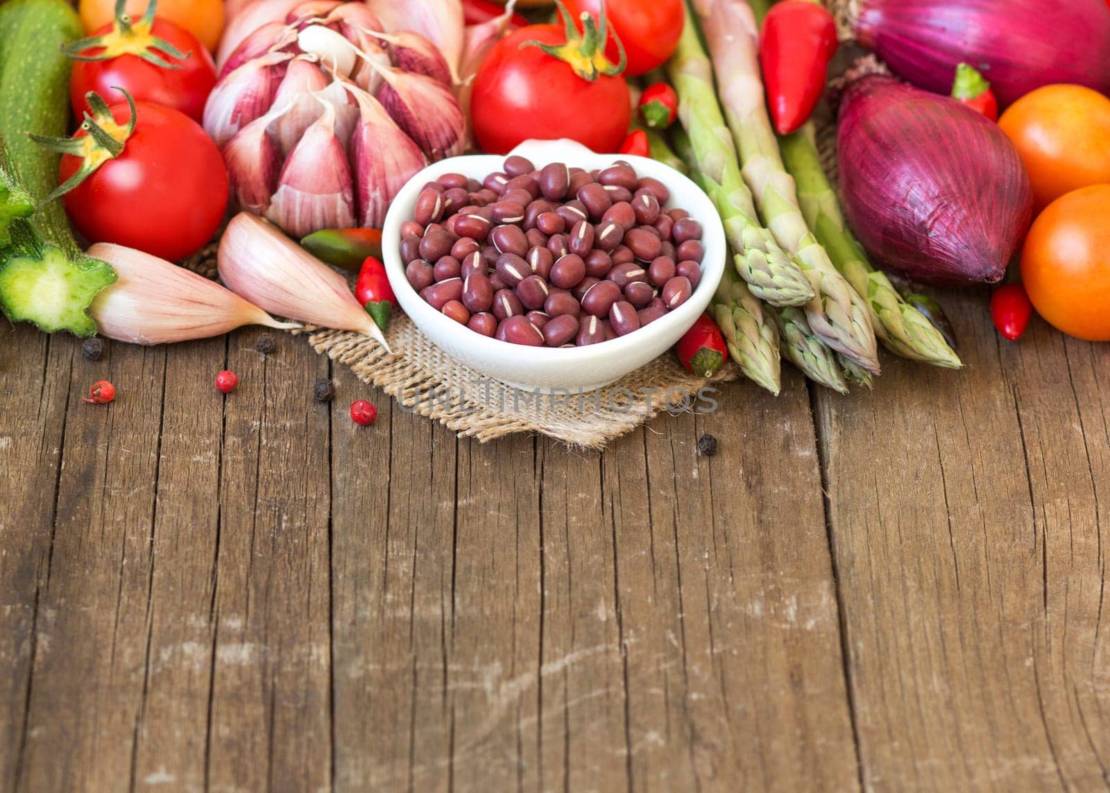 Azuki beans in a bowl and vegetables on wooden table