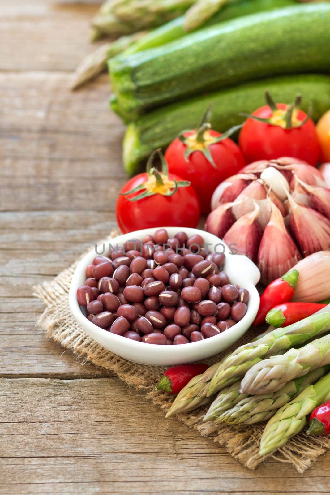 Azuki beans in a bowl and vegetables on wooden table