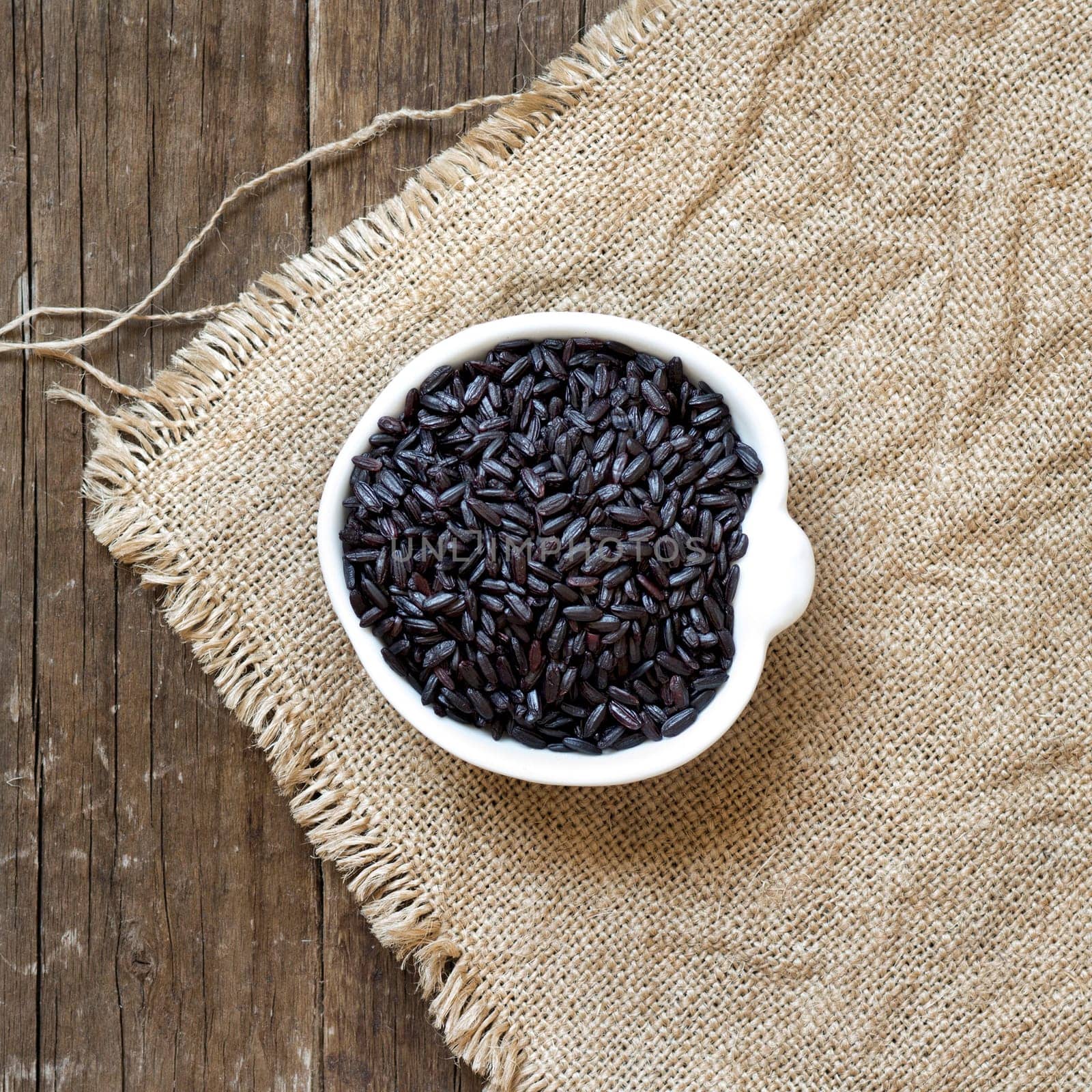 Raw black rice in a bowl on burlap