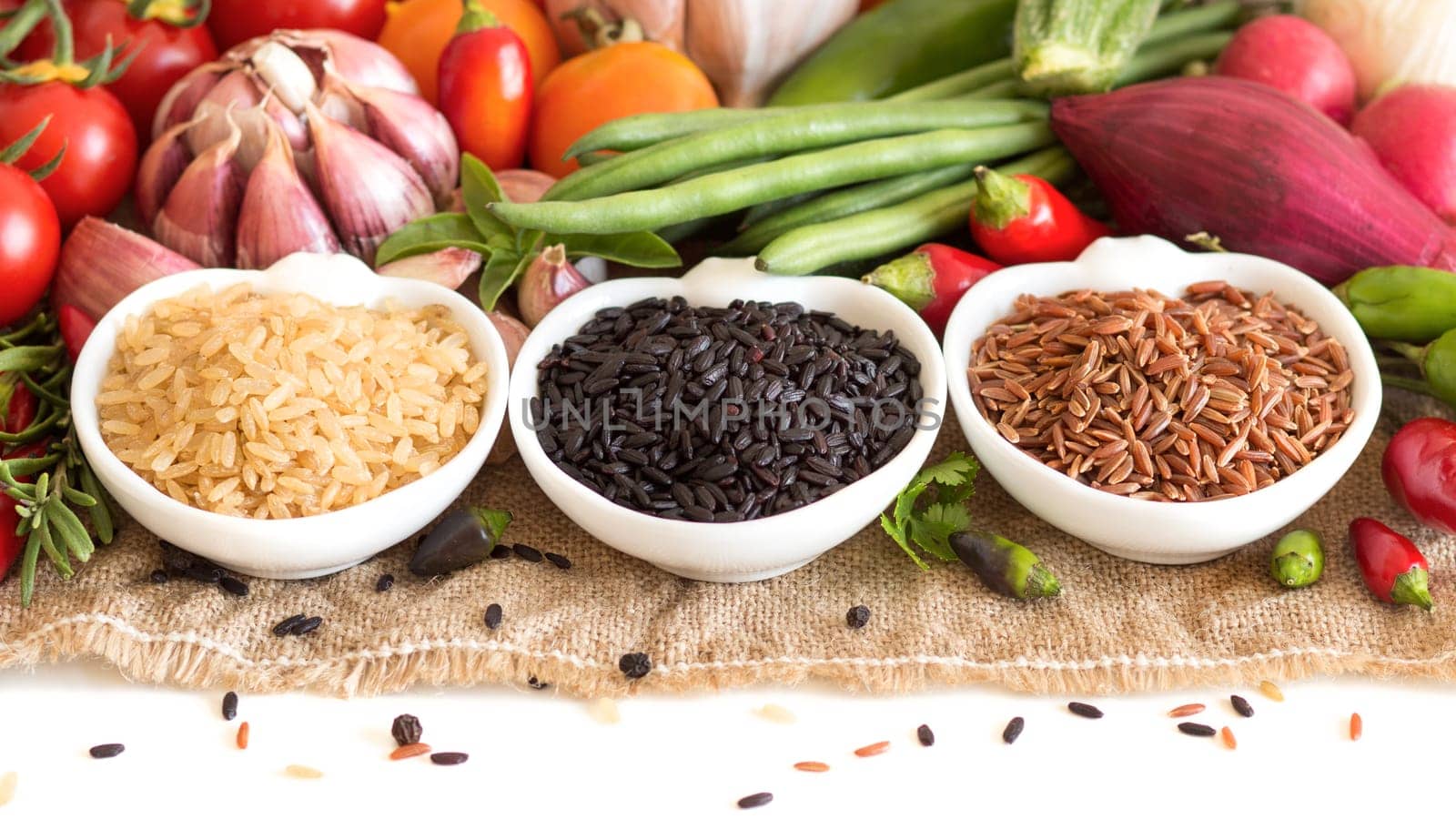 Red, black and unpolished organic rice in bowls and vegetables