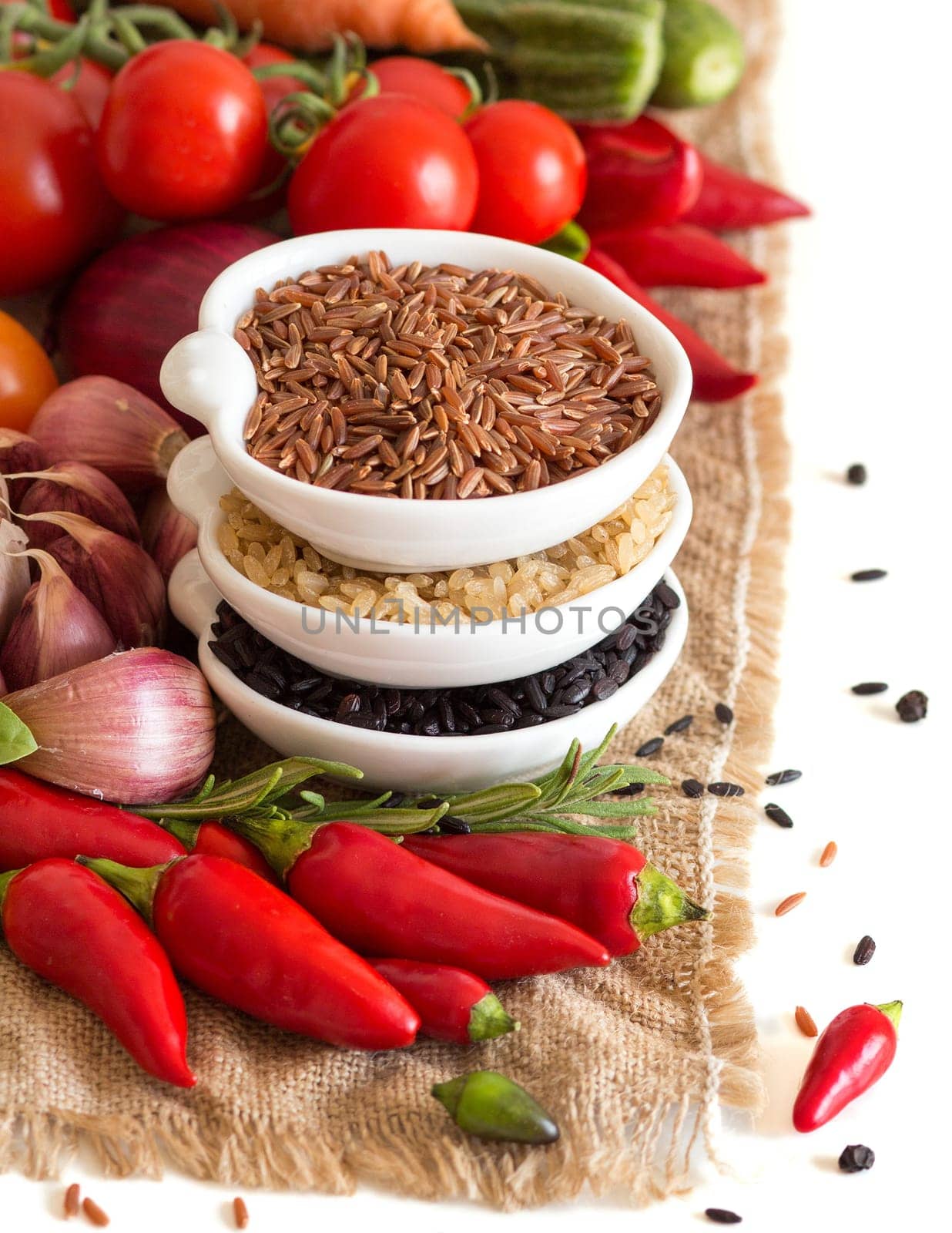 Red, black and unpolished organic rice in bowls and vegetables