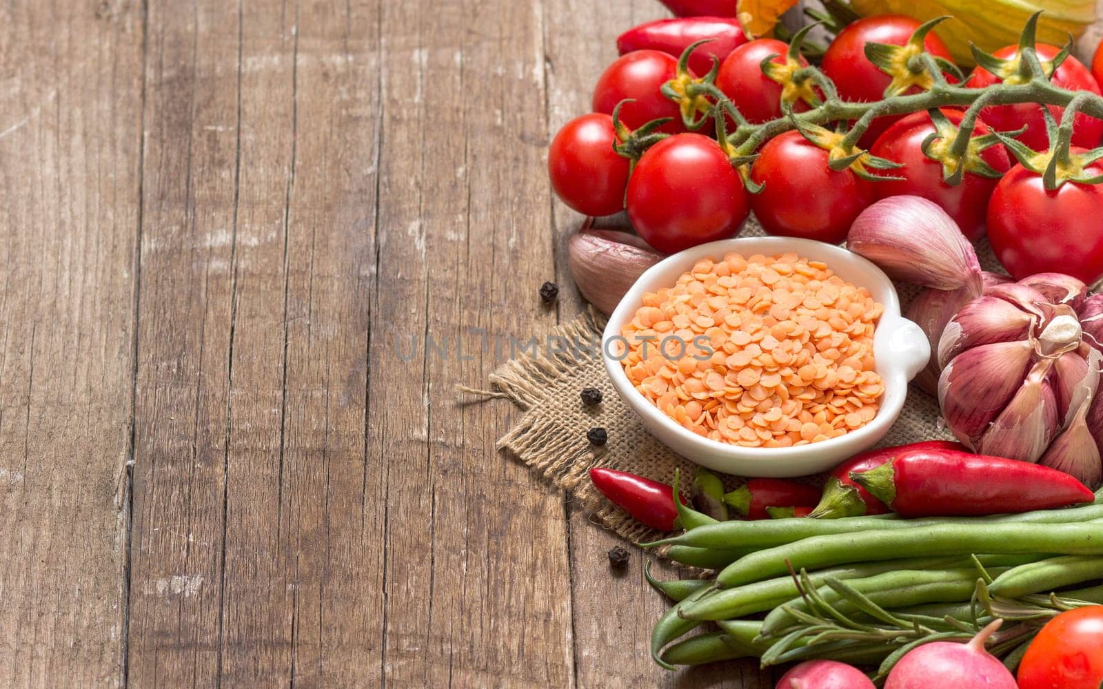 Red lentils in bowl and vegetables on a wooden table