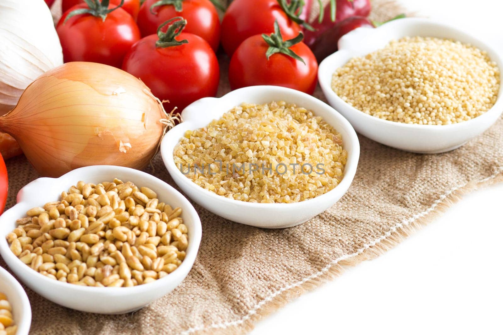 Millet, spelt, bulgur and vegetables on wooden table
