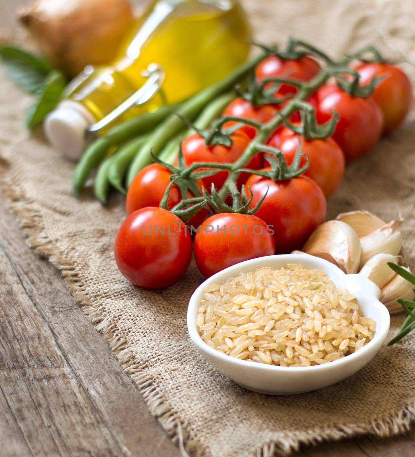 Red organic rice, vegetables and herbs on wooden background