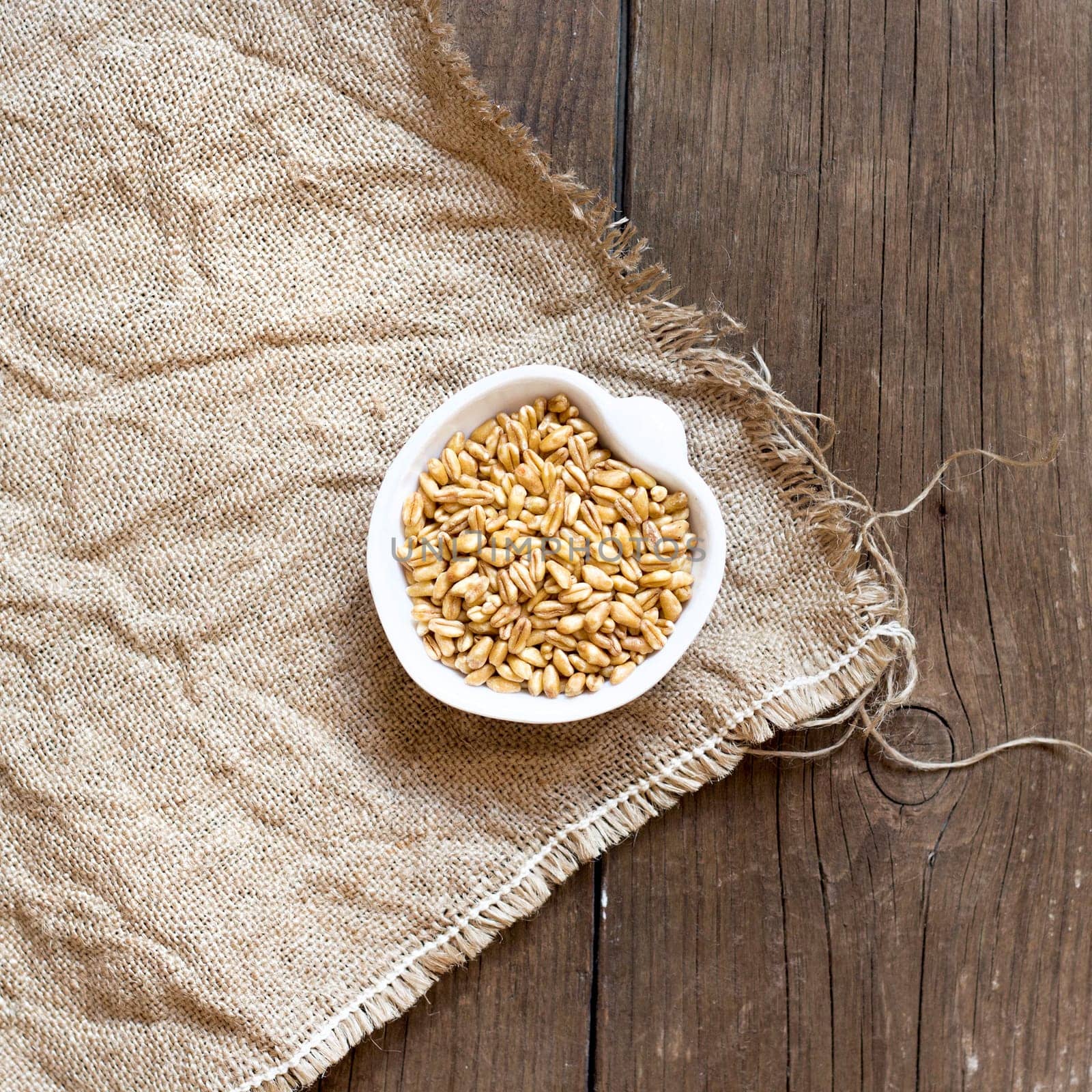 Raw Organic wheat grain in a bowl on wooden table