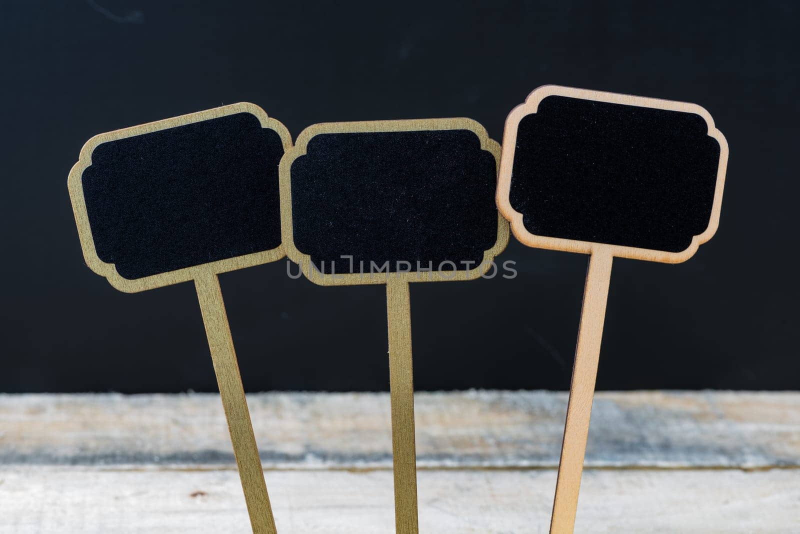 Wooden mini blackboard labels over chalkboard background and table, copy space available