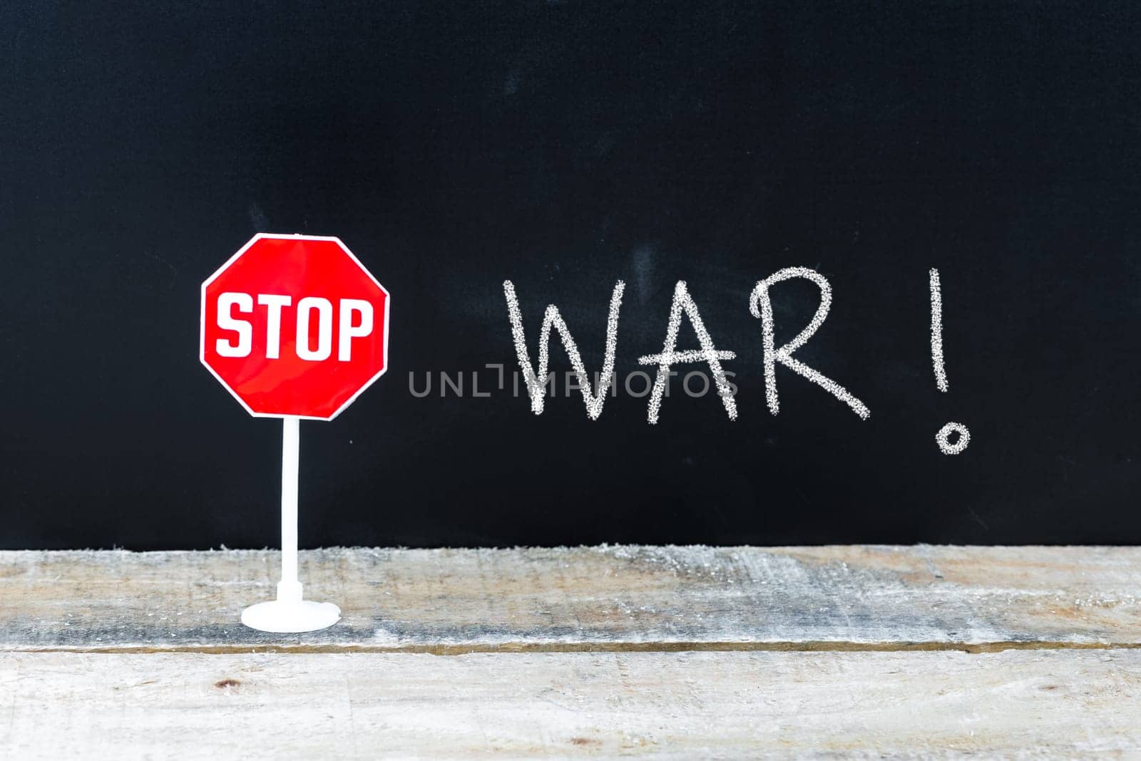 Mini STOP sign over chalkboard background and table, STOP WAR concept