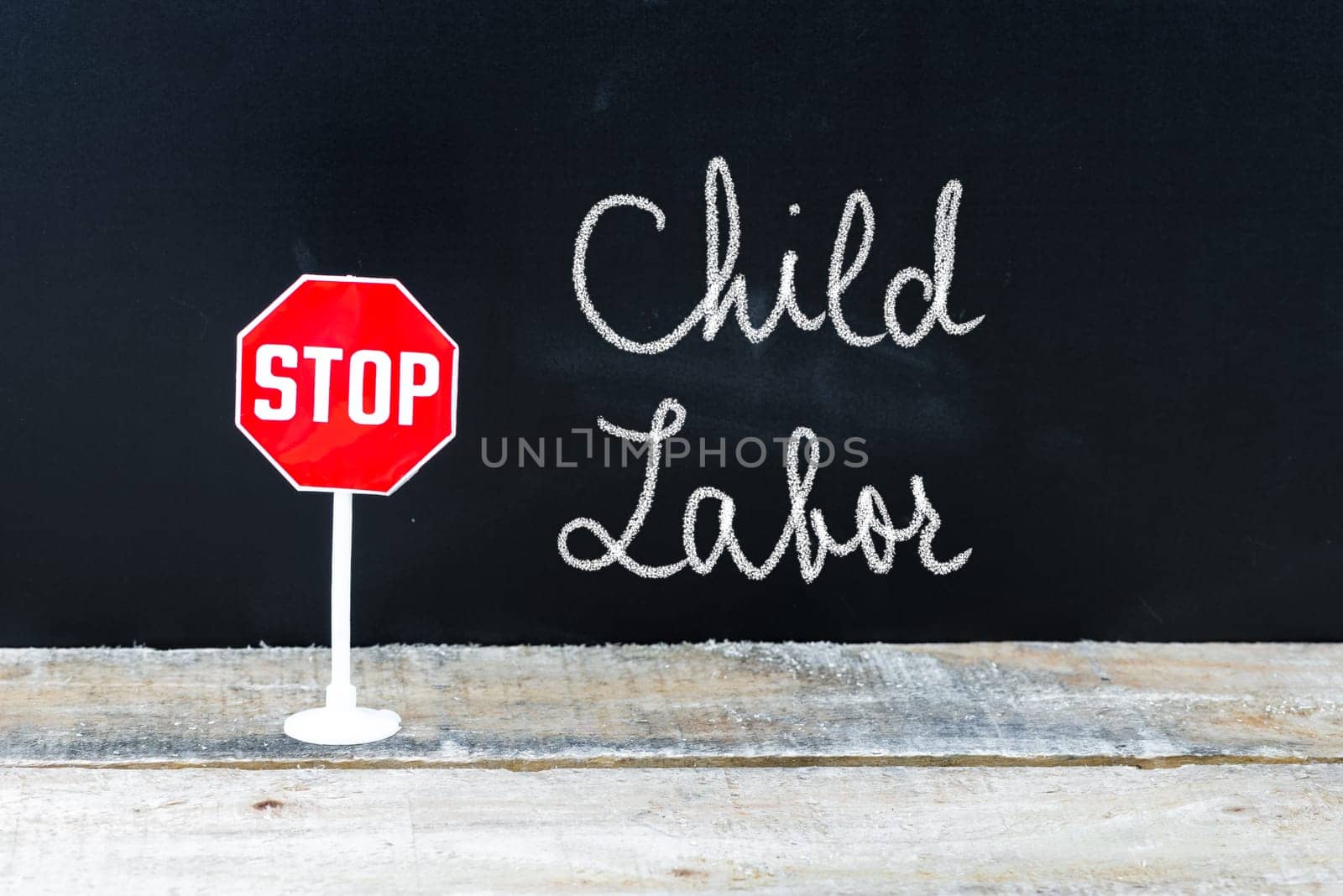 Mini STOP sign over chalkboard background and table, STOP CHILD LABOR concept