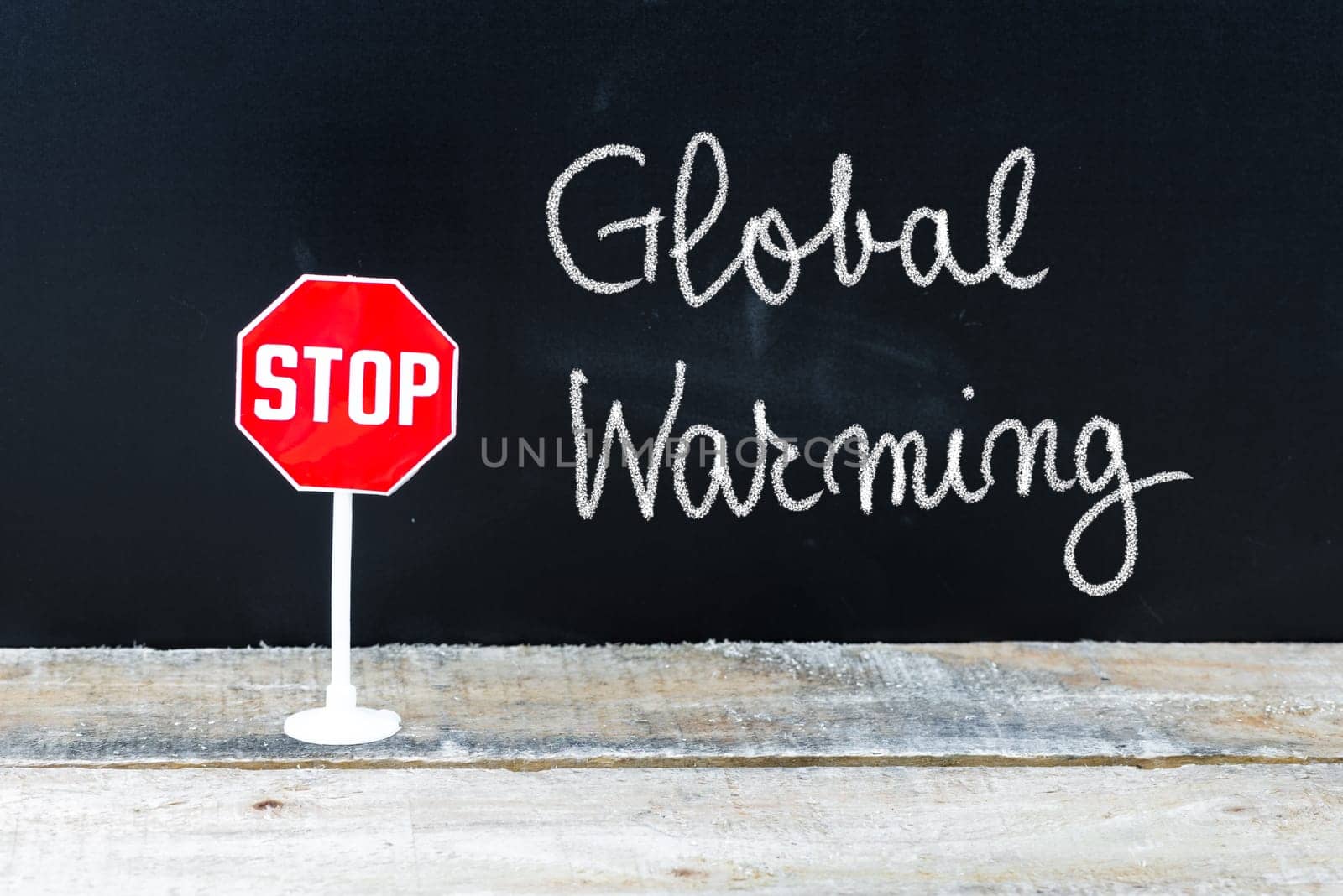 Mini STOP sign over chalkboard background and table, STOP GLOBAL WARMING concept