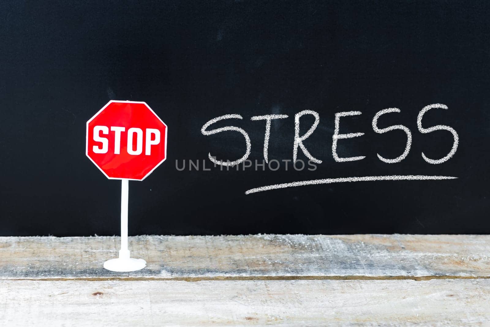 Mini STOP sign over chalkboard background and table, STOP STRESS concept