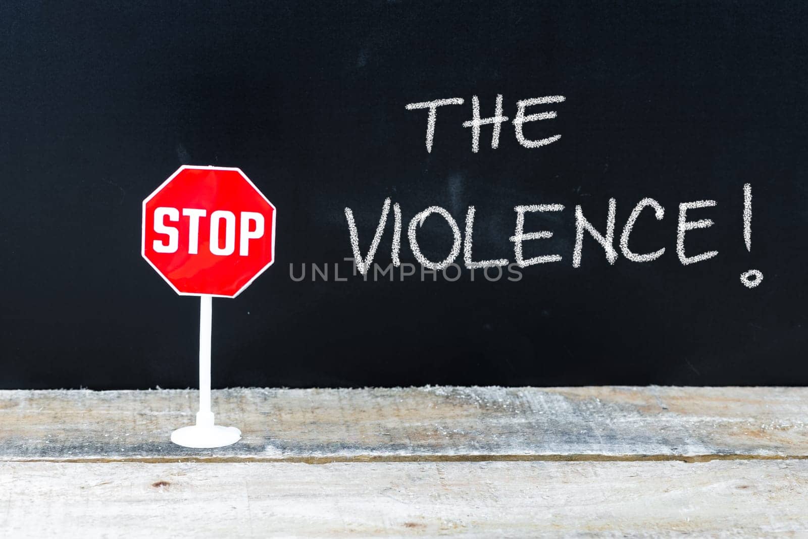 Mini STOP sign over chalkboard background and table, STOP THE VIOLENCE concept