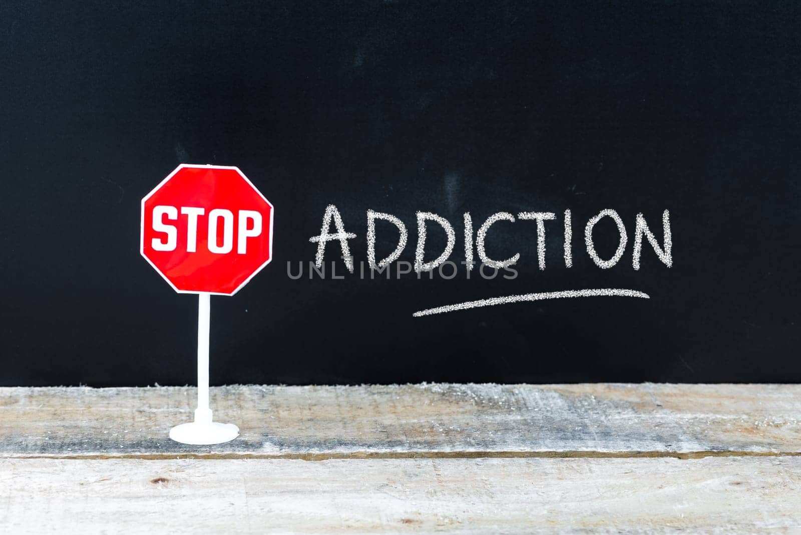 Mini STOP sign over chalkboard background and table, STOP ADDICTION concept