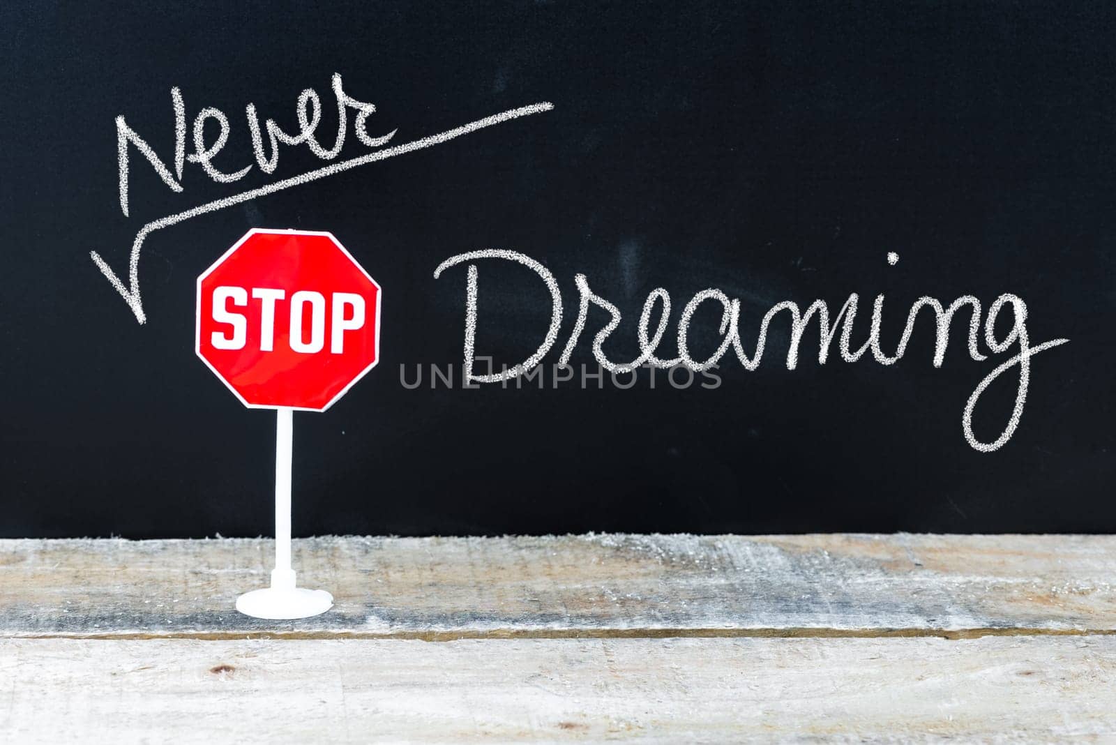 Mini STOP sign over chalkboard background and table, NEVER STOP DREAMING concept