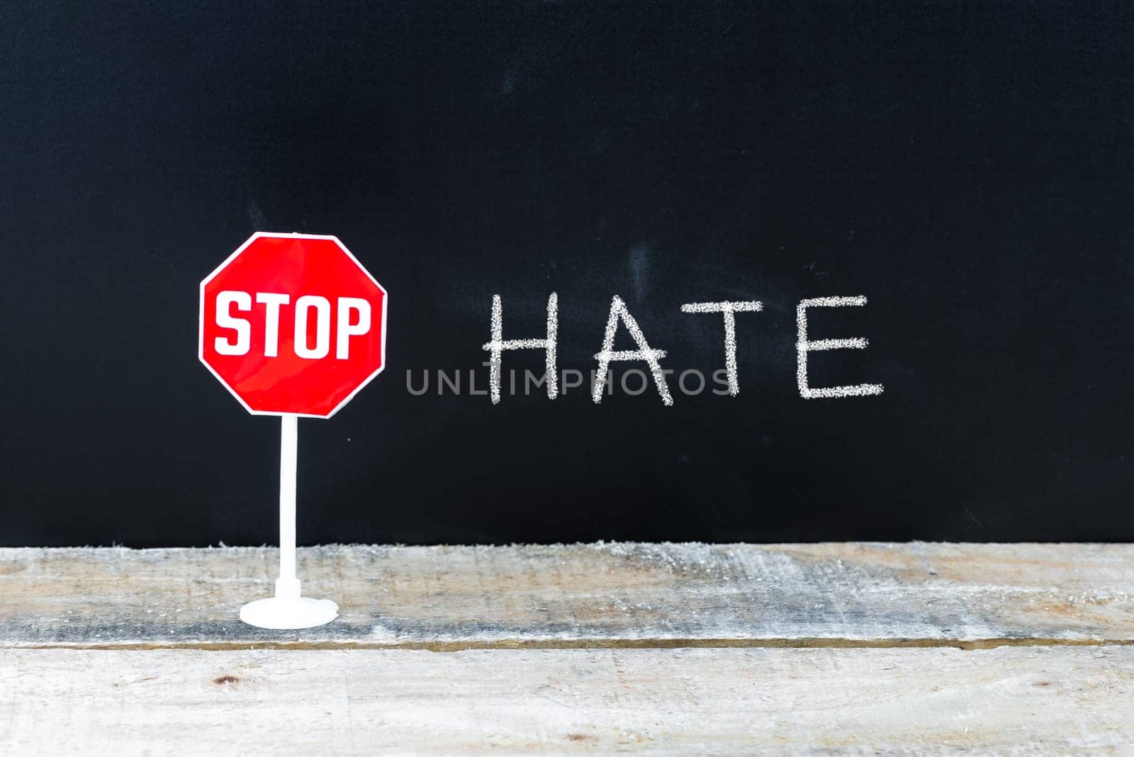 Mini STOP sign over chalkboard background and table, STOP HATE concept