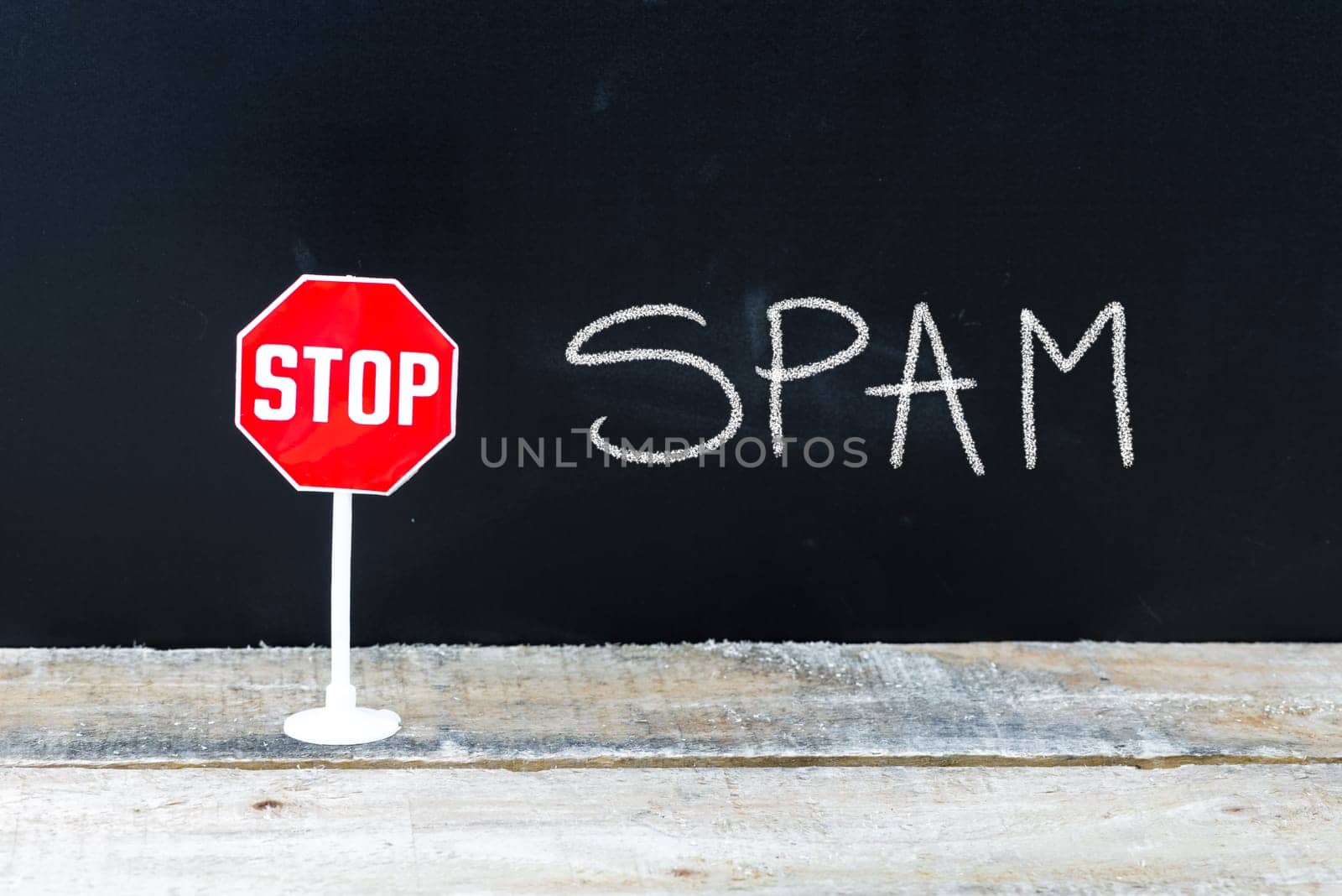Mini STOP sign over chalkboard background and table, STOP SPAM concept