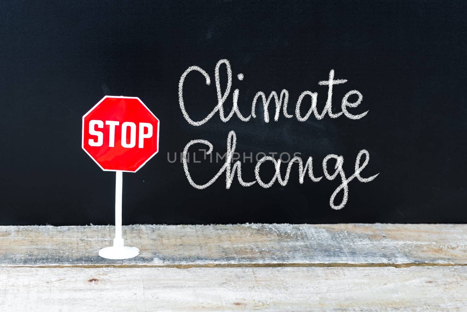 Mini STOP sign over chalkboard background and table, STOP CLIMATE CHANGE concept