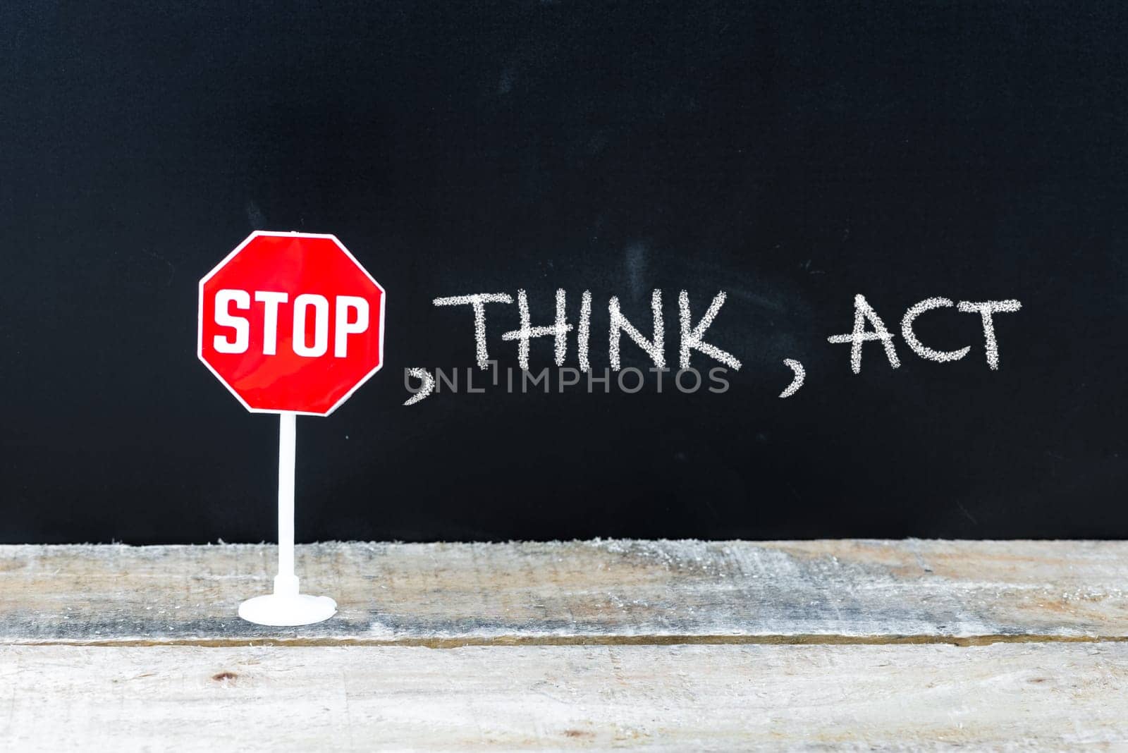 Mini STOP sign over chalkboard background and table, STOP, THINK, ACT concept