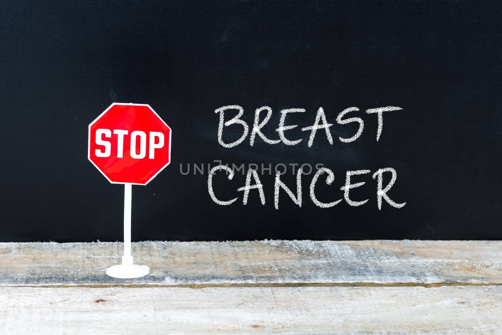 Mini STOP sign over chalkboard background and table, STOP BREAST CANCER concept