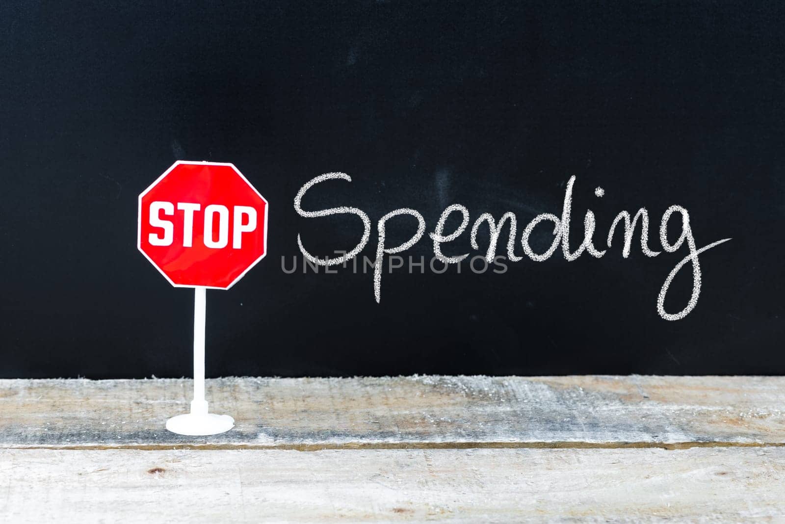 Mini STOP sign over chalkboard background and table, STOP SPENDING concept