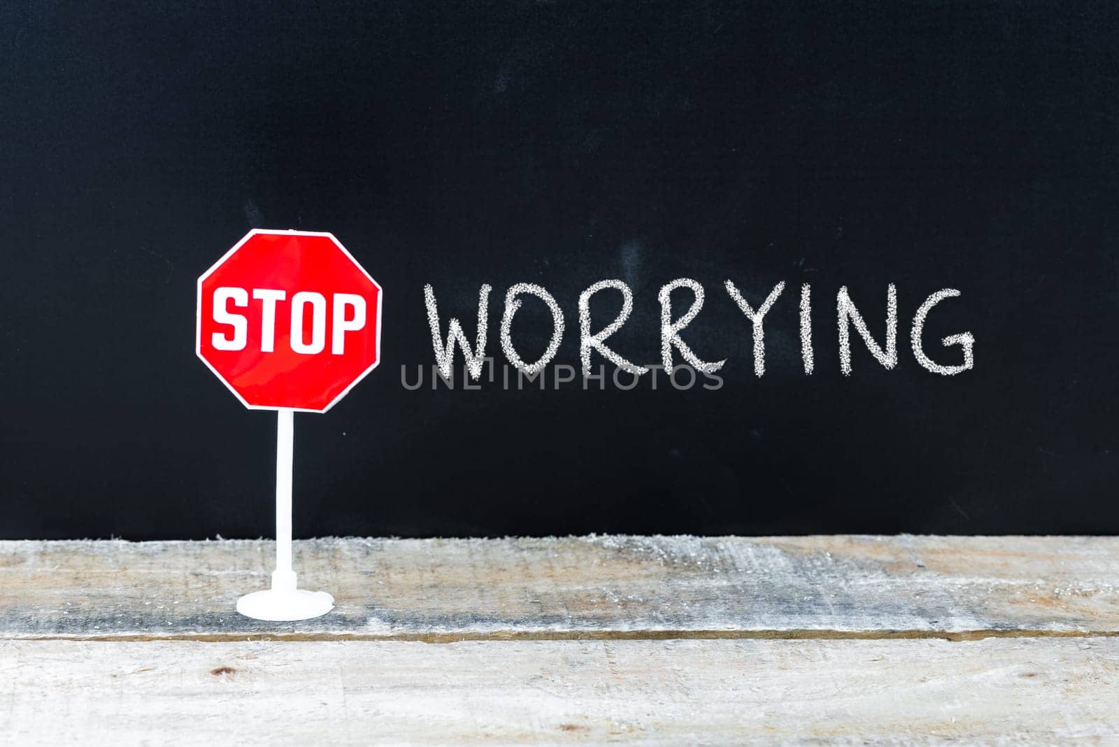 Mini STOP sign over chalkboard background and table, STOP WORRYING concept