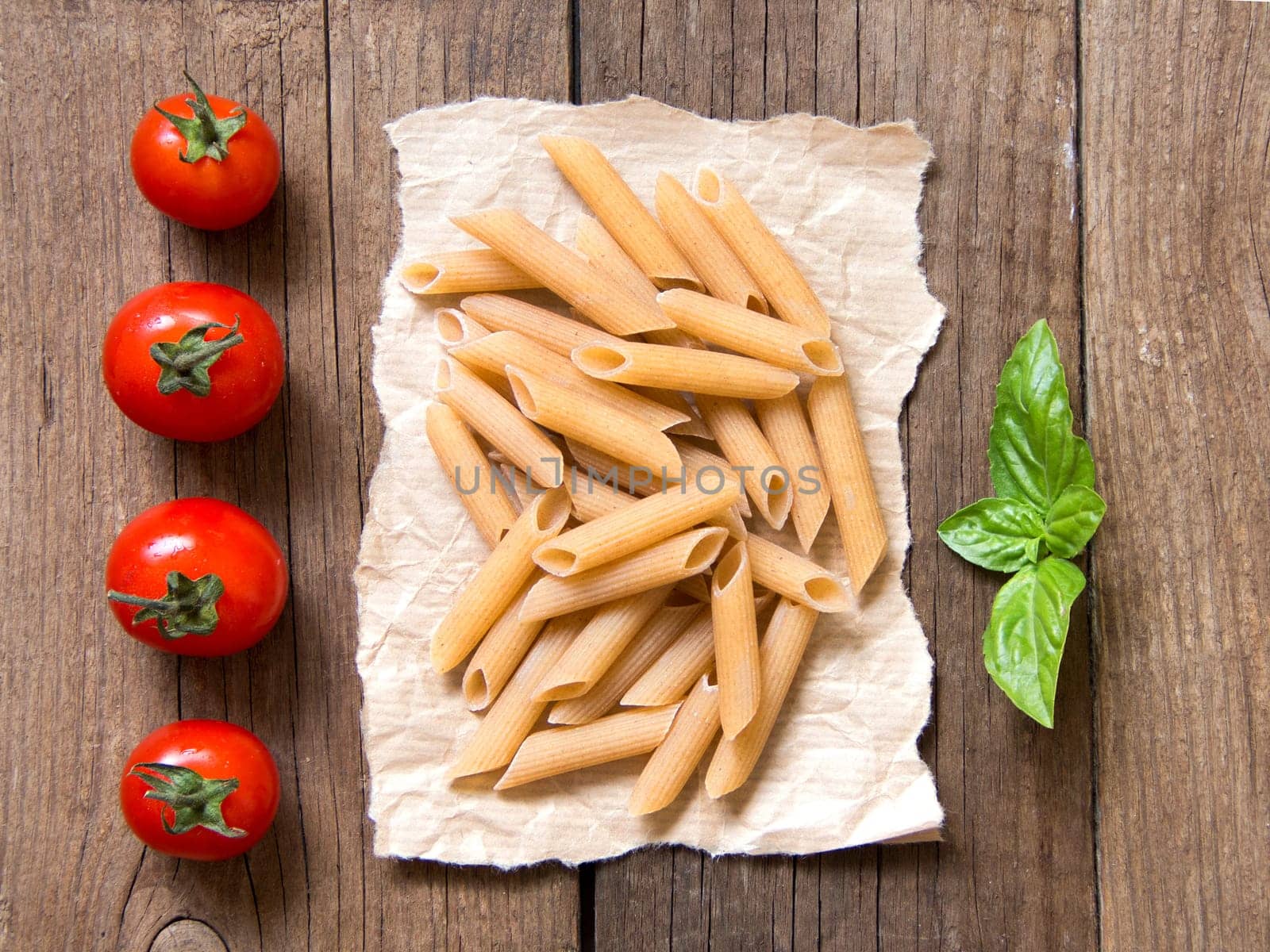 Pasta, tomatoes and basil on wooden background