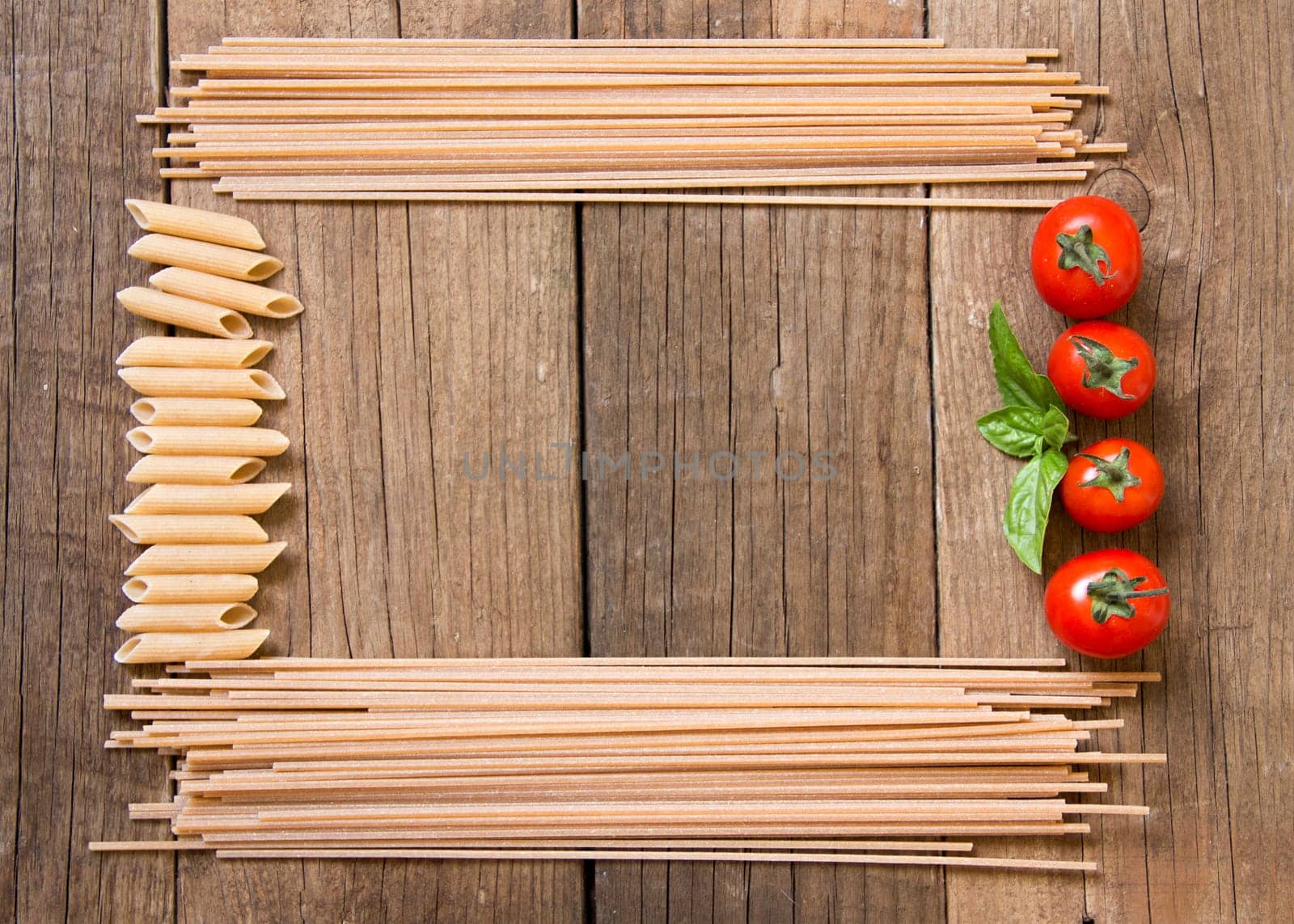 Pasta, tomatoes and basil on wooden background