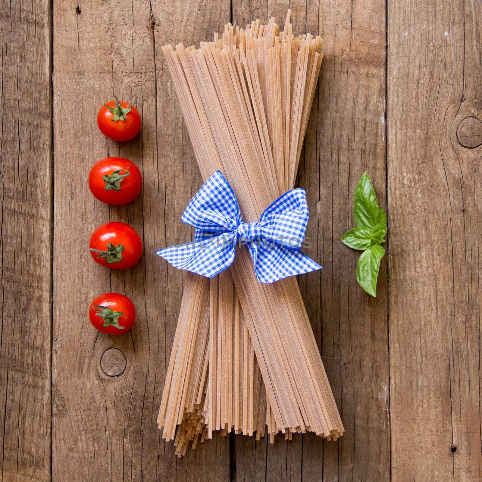 Pasta, tomatoes and basil on wooden background