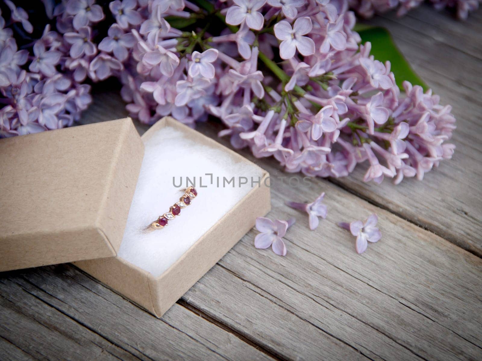 Ring in gift box and lilac on wood