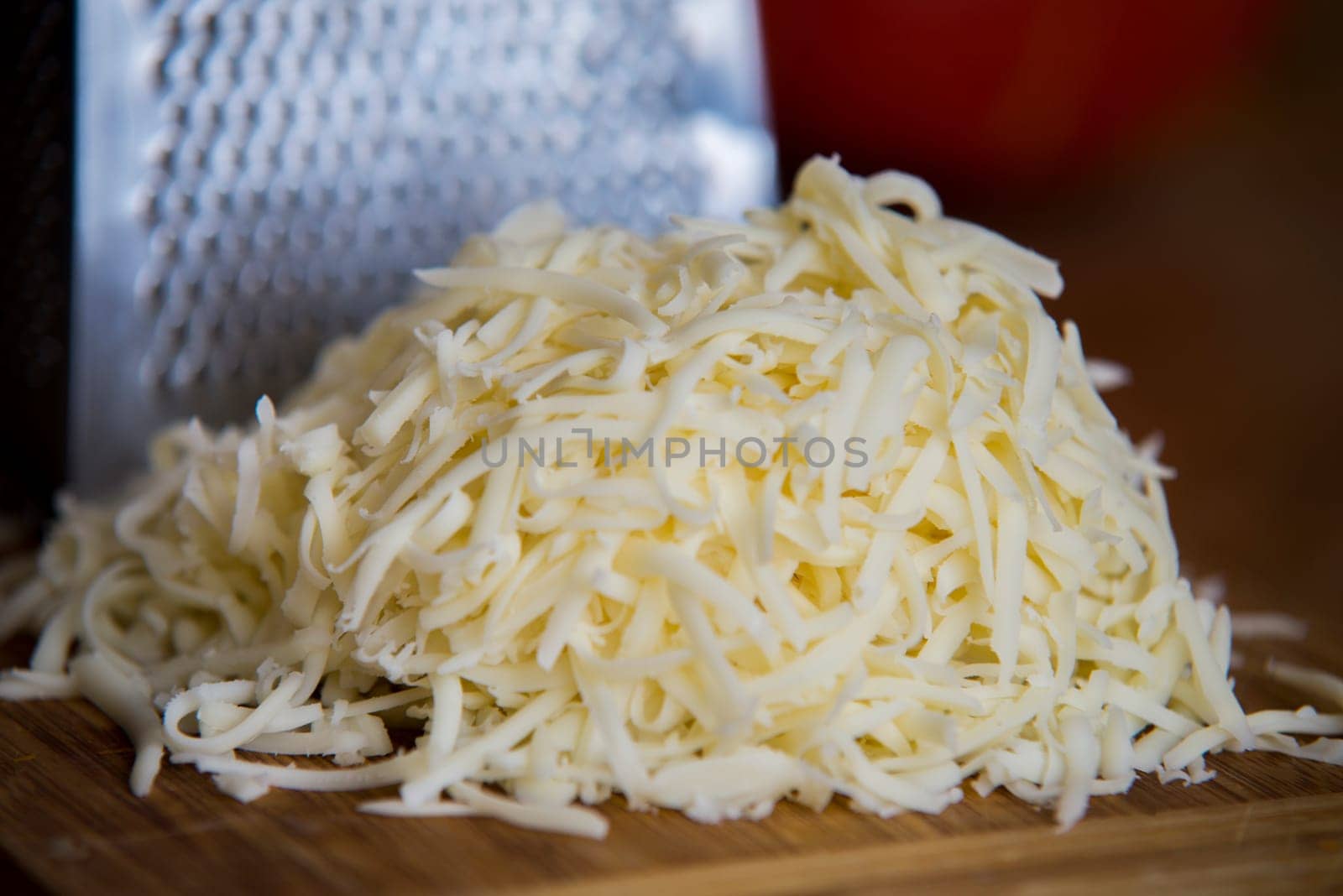 shredded mozzarella cheese on a cutting board with a grater